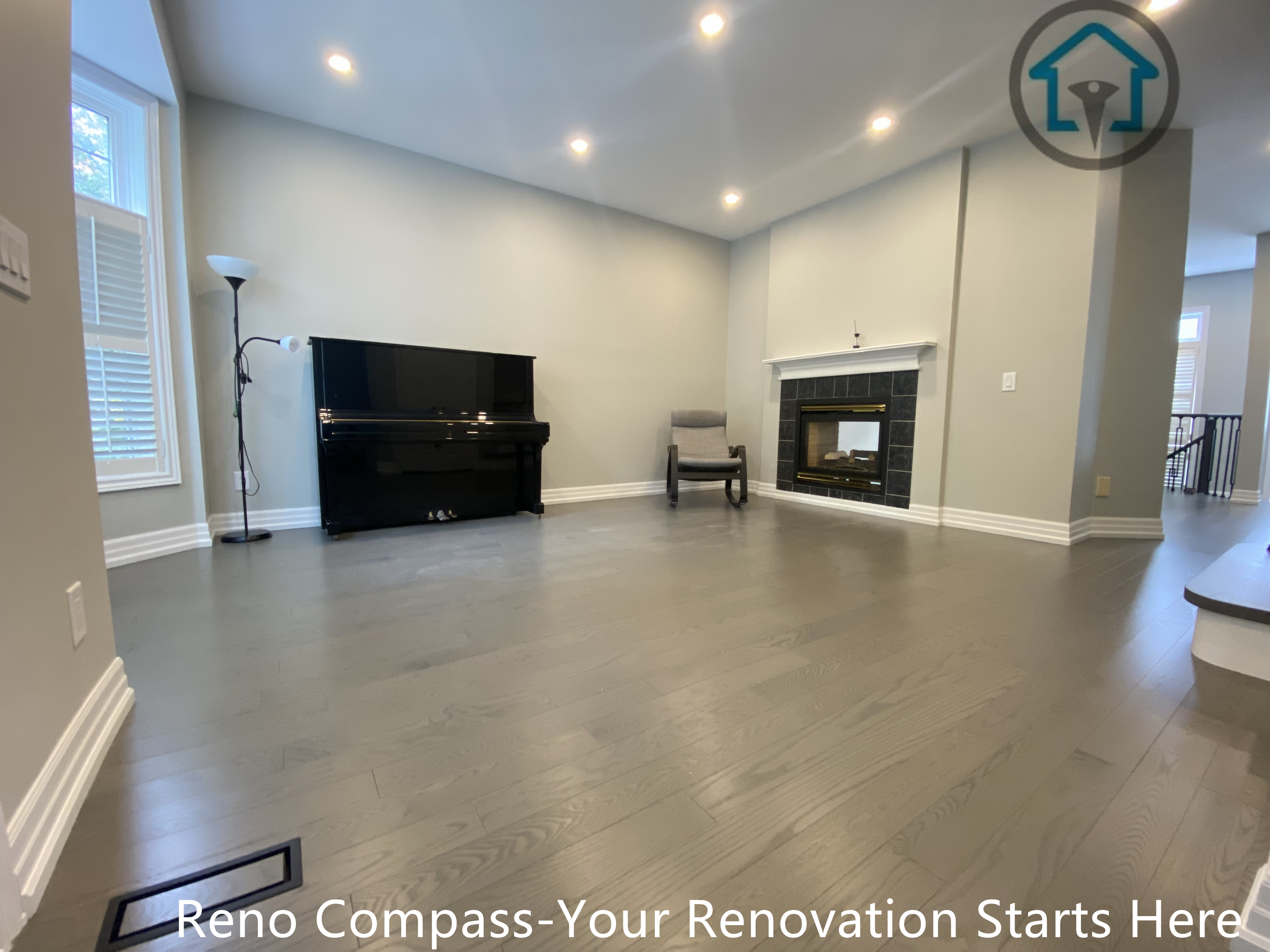 This open-concept living room renovation features wide-plank flooring, recessed ceiling lighting, and a clean, neutral palette that enhances brightness and spatial flow. The fireplace serves as a subtle focal point while maintaining a calm, uncluttered layout suitable for everyday living. Improved lighting distribution and refined finishes create a balanced, welcoming space that integrates seamlessly with the surrounding staircase and upper level, completed as part of a full interior renovation by Reno Compass.