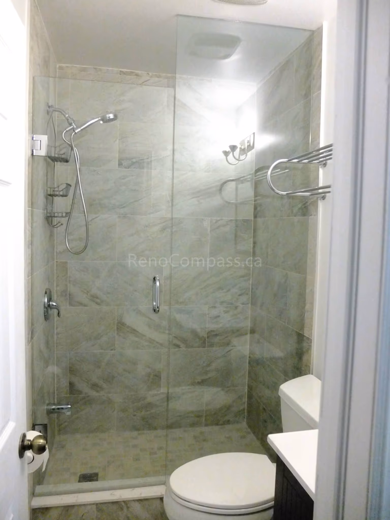 This North York bathroom renovation showcases a modern walk-in glass shower with full-height marble-look tile walls, upgraded fixtures, and a clean space-saving layout. Completed by a professional Toronto renovation company, the project focuses on maximizing functionality, improving lighting, and creating a bright, elegant bathroom with durable materials and precise finishing details.