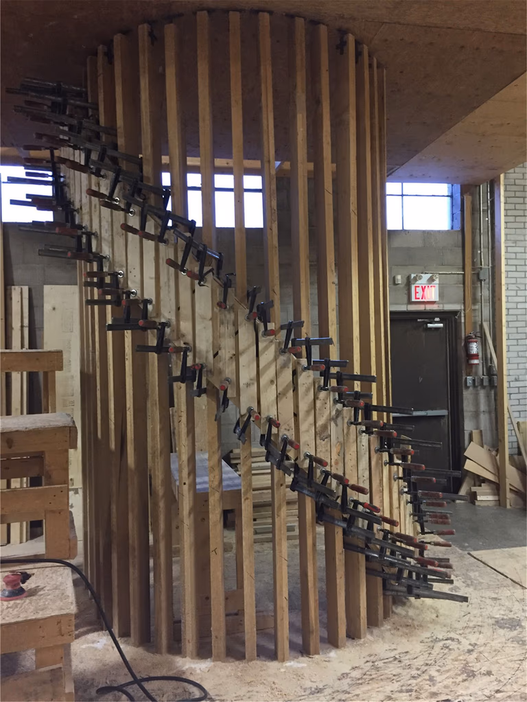 This image shows the construction phase of a custom curved staircase during a Toronto stair renovation project. Vertical wood framing and precision clamping techniques are used to shape the staircase structure, ensuring accurate curvature and strong structural support. The carefully aligned framing demonstrates skilled craftsmanship required for complex staircase designs. As a professional Toronto Renovation Company, Reno Compass Inc. specializes in custom staircase construction, delivering durable and architecturally striking stair solutions for homes and commercial spaces across Toronto and the GTA.