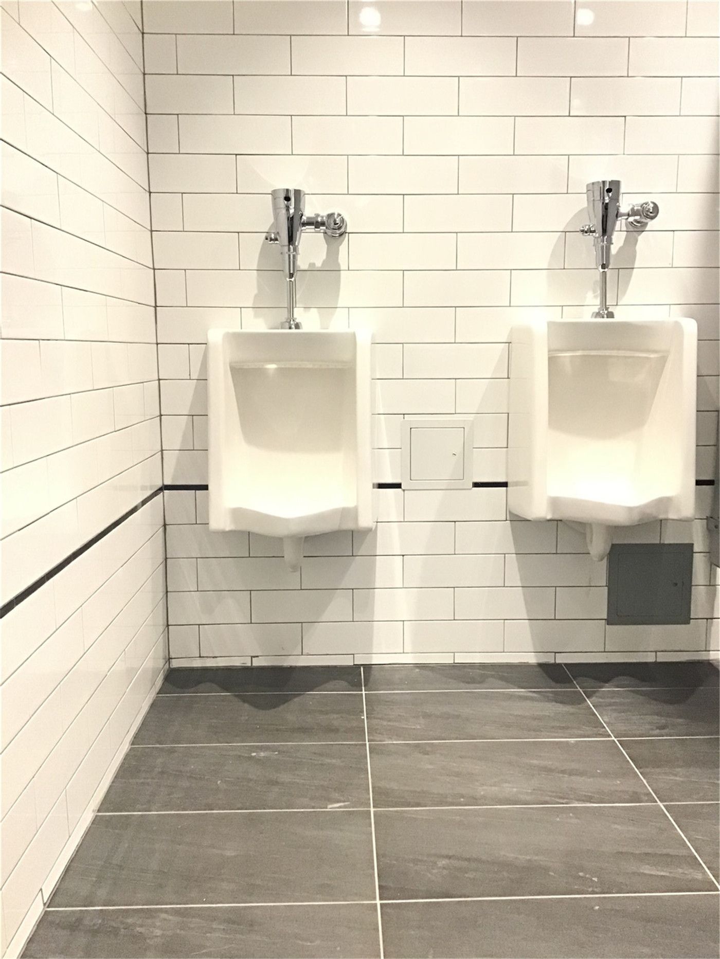 Commercial washroom renovation in downtown Toronto featuring wall-mounted urinals, white subway tile walls, and durable tile flooring, designed for functionality, hygiene, and high-traffic business environments.
