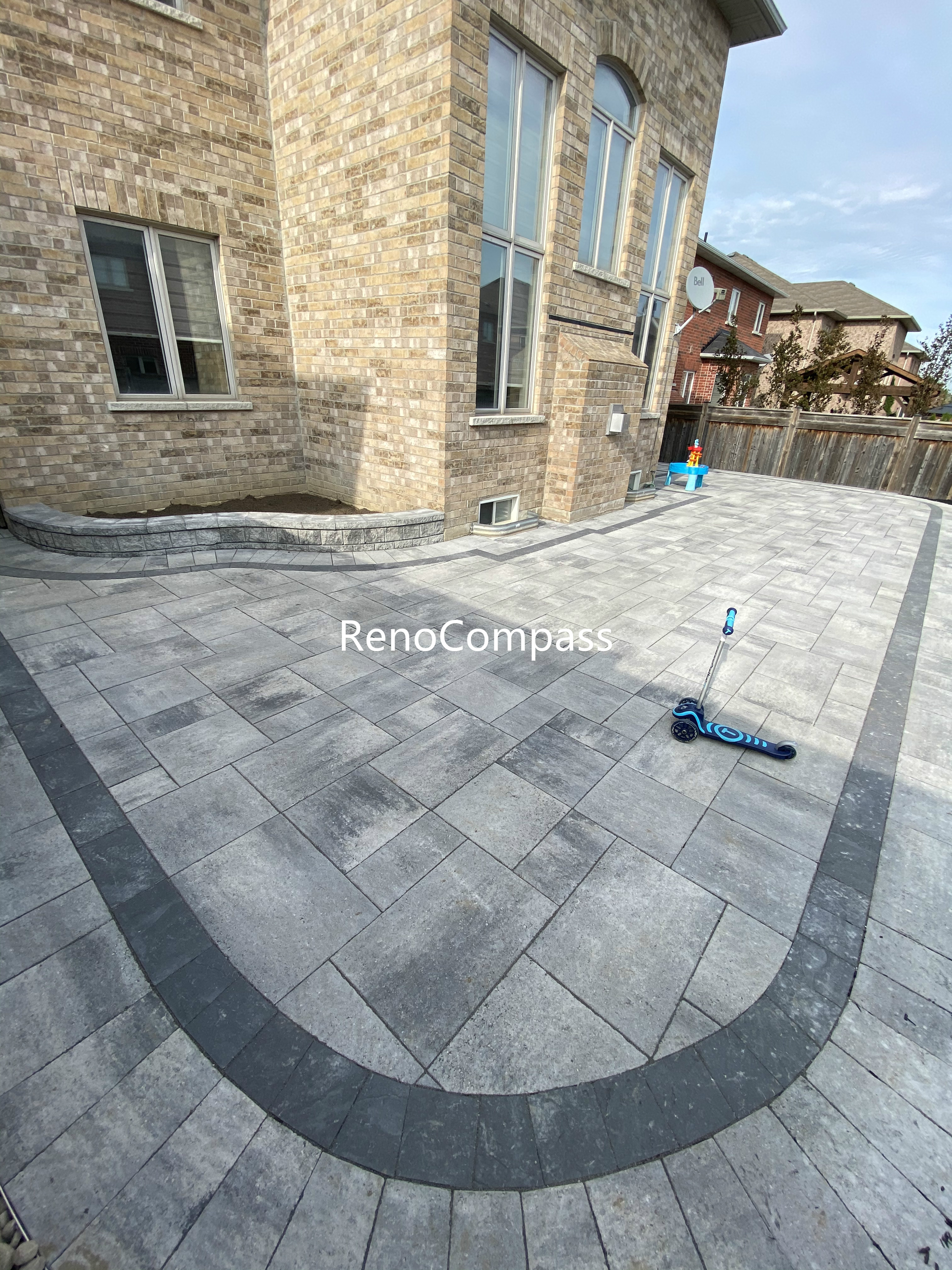 This Aurora backyard interlocking paver patio features a spacious layout with a curved border design that adds visual flow and architectural interest. Large-format concrete pavers are arranged in a clean, linear pattern, while the contrasting border enhances structure and edge definition. The durable interlock surface provides excellent drainage, stability, and low maintenance, making it ideal for daily use and outdoor activities. This professionally completed backyard paving project improves both functionality and aesthetics, offering a modern outdoor living space for residential properties in Aurora.