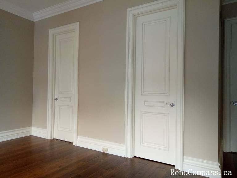 This image presents a completed interior painting project in North York, showcasing a clean hallway space with freshly painted walls, detailed door trim, and crisp crown molding. The soft neutral wall color enhances the depth of the corridor while complementing the white doors and trim for a refined, cohesive look. Smooth transitions between walls, ceilings, and baseboards highlight careful preparation and professional application. This North York painting project reflects high-quality craftsmanship, creating a bright and elegant interior finish suitable for hallways and connecting spaces.