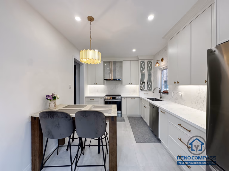 This Markham kitchen renovation showcases a well-balanced U-shaped layout with custom white cabinetry, quartz countertops, and integrated under-cabinet lighting. A compact dining island with seating adds functionality without interrupting workflow, making the space ideal for both daily use and casual gatherings. The gold pendant light introduces a warm focal point, while clean lines and modern appliances keep the overall design bright, efficient, and timeless.