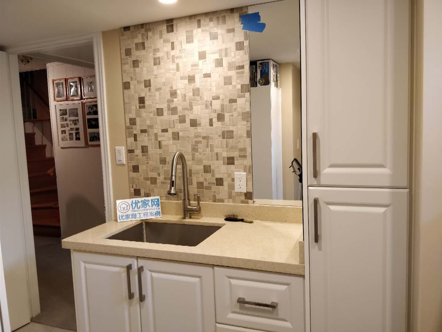 Modern basement wet bar area completed during a Scarborough interior renovation project. The space features custom white cabinetry, quartz countertop, mosaic tile backsplash, and a stainless steel sink with a modern faucet, creating a clean and functional entertainment area for the home.