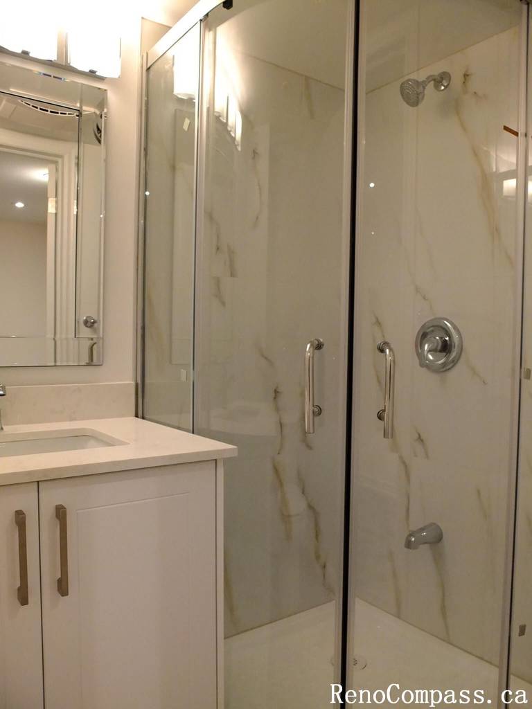 This Markham basement renovation features a modern bathroom design with a frameless glass shower enclosure, marble-look wall tiles, and a sleek white vanity with integrated sink. The bright finishes and contemporary fixtures create a clean, elegant, and highly functional basement bathroom space for homeowners in Markham.