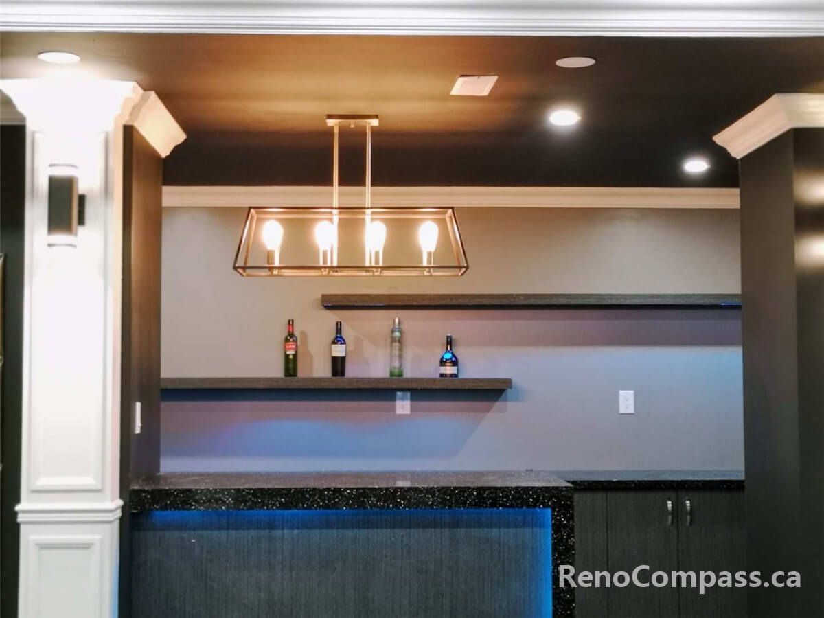 This image showcases a custom-built bar area within a home theater project, featuring modern cabinetry, floating shelves, accent lighting, and ceiling-mounted fixtures that enhance both functionality and entertainment atmosphere.