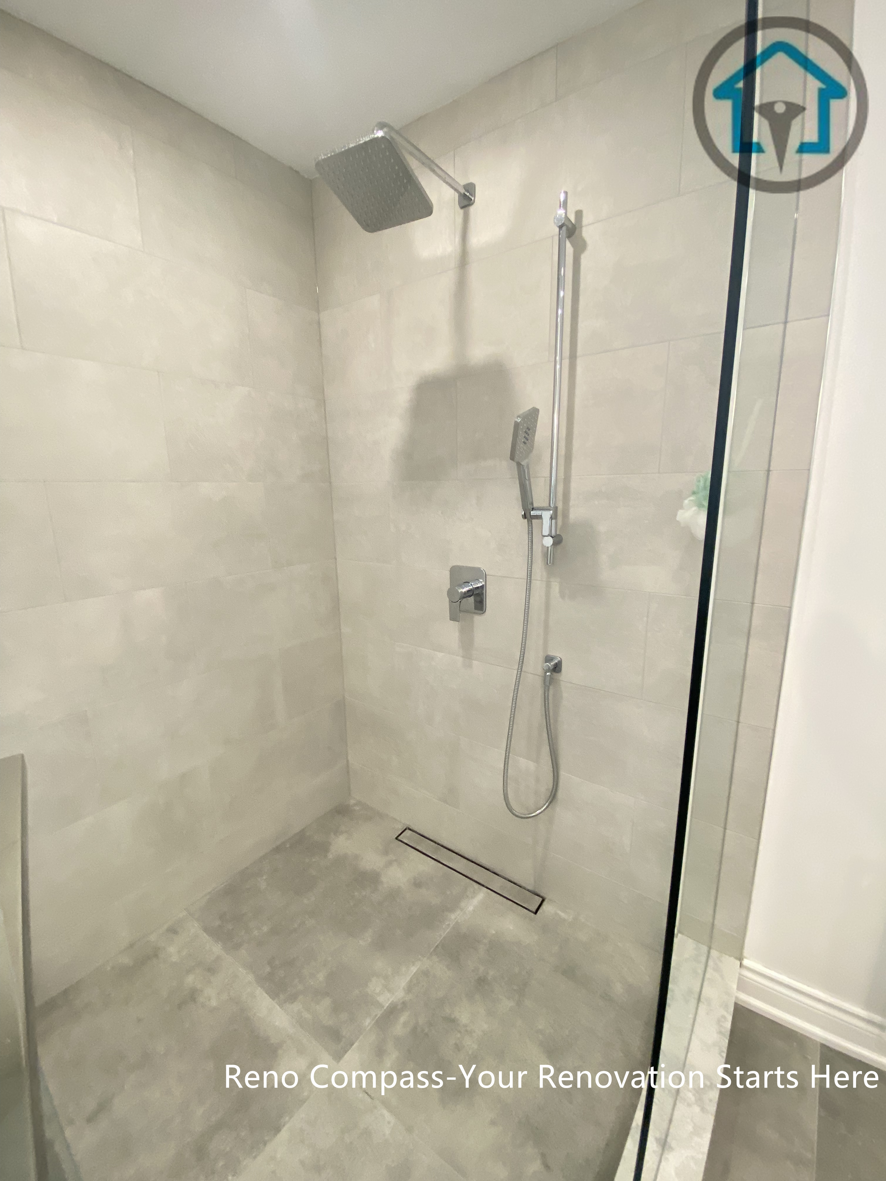 This Oakville bathroom renovation features a modern walk-in shower with large-format grey tiles and a linear floor drain for a clean, seamless look. The frameless glass enclosure enhances openness, while the neutral stone tones create a calm and contemporary atmosphere. Designed for easy maintenance and everyday comfort, this shower layout balances practicality with timeless modern style.