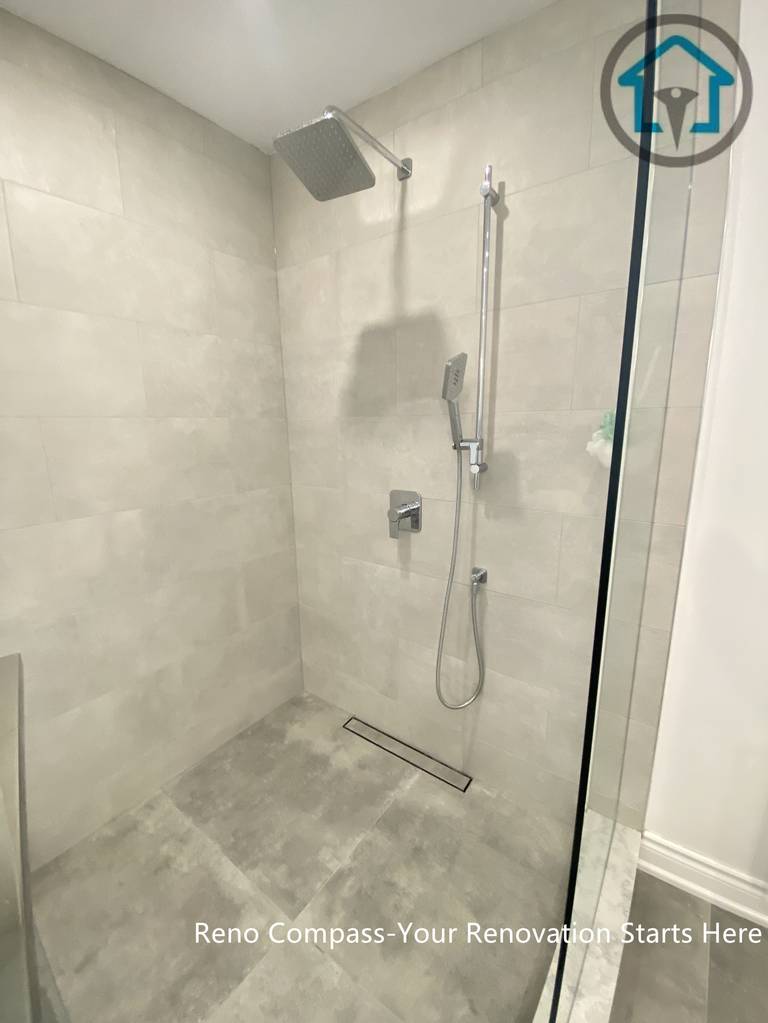 This Oakville bathroom renovation features a modern walk-in shower with large-format grey tiles and a linear floor drain for a clean, seamless look. The frameless glass enclosure enhances openness, while the neutral stone tones create a calm and contemporary atmosphere. Designed for easy maintenance and everyday comfort, this shower layout balances practicality with timeless modern style.