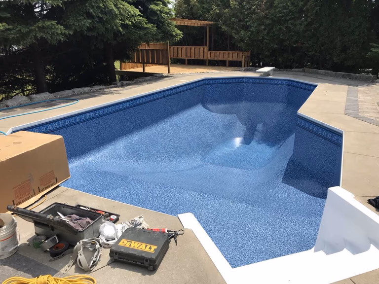 After renovation photo of a fully restored backyard swimming pool in Toronto. The new bright blue liner, clean water, and resurfaced edges highlight the professional pool transformation from old and damaged to modern and inviting. Expert pool renovation by local Toronto specialists.