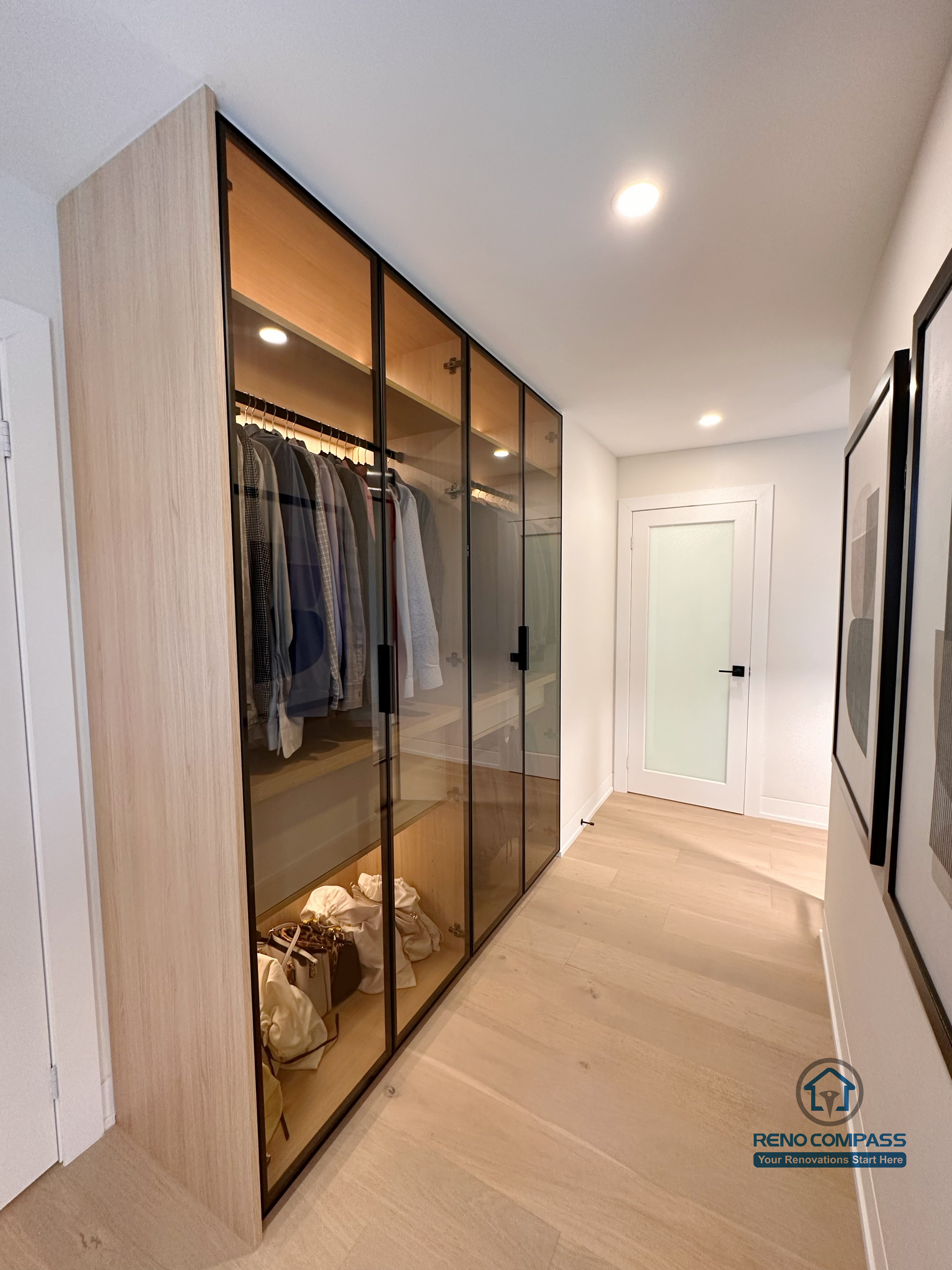 A custom walk-in closet renovation in Toronto featuring floor-to-ceiling glass wardrobe cabinetry with integrated LED lighting. This bespoke storage solution enhances organization and visibility while maintaining a sleek, modern look, completed by a professional Toronto renovation company.