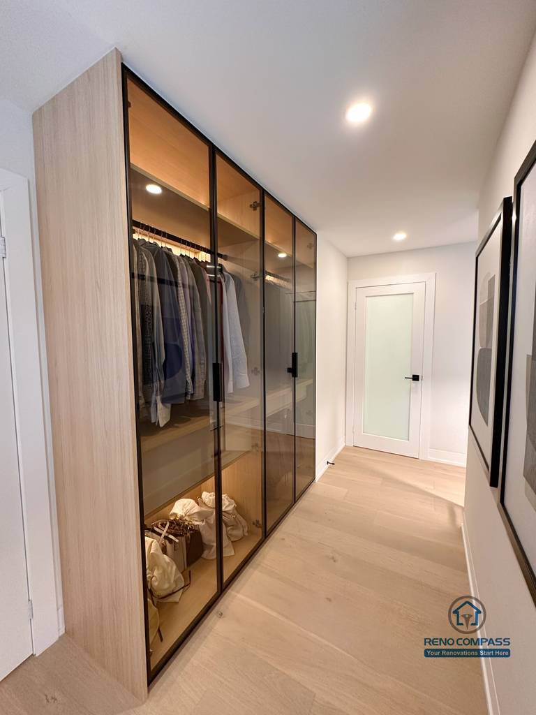 A custom walk-in closet renovation in Toronto featuring floor-to-ceiling glass wardrobe cabinetry with integrated LED lighting. This bespoke storage solution enhances organization and visibility while maintaining a sleek, modern look, completed by a professional Toronto renovation company.