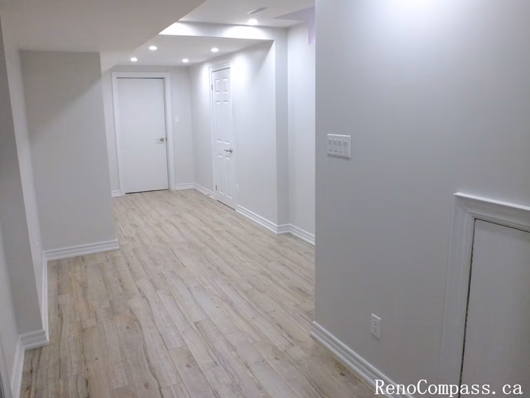 Bright hallway in a renovated Richmond Hill basement featuring new floors, recessed lighting, and elegant white finishes by Reno Compass