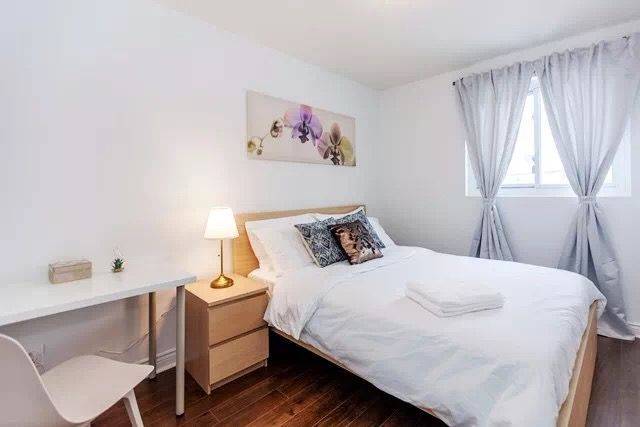 This Toronto interior renovation features a bright and cozy bedroom with clean white walls, minimalist furniture, and soft decorative accents. The space includes a comfortable bed, modern bedside lighting, and simple artwork that enhances the calm atmosphere. The renovation creates a relaxing and functional bedroom environment, perfect for comfortable living in a modern Toronto home.
