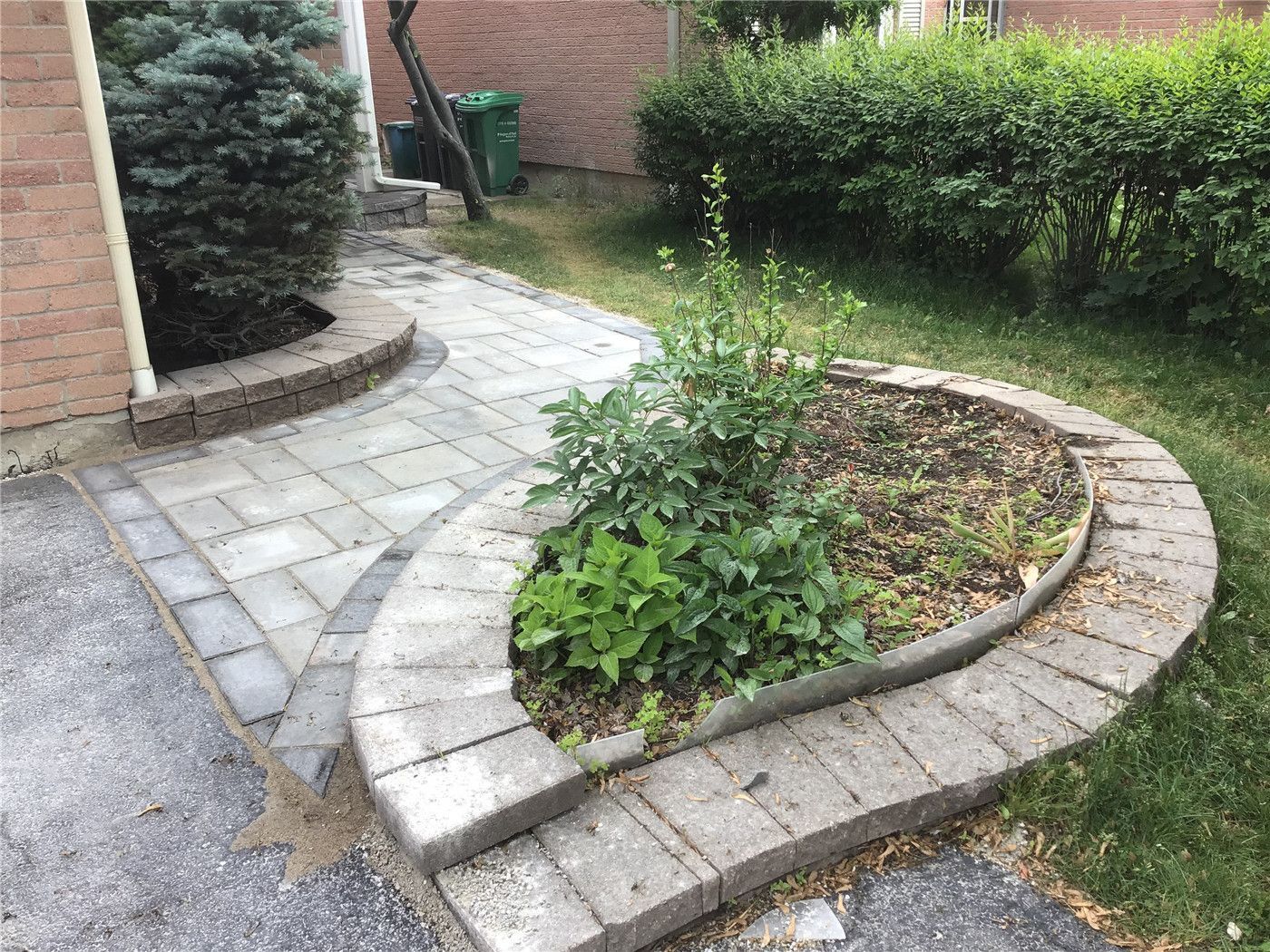 This Oakville interlocking project features a beautifully curved walkway integrated with a raised garden bed and natural stone borders. The soft curve design enhances the landscape flow while maintaining a clean and structured layout. Built with durable grey pavers, this installation improves accessibility, drainage, and curb appeal, creating a harmonious blend between hardscape and greenery.