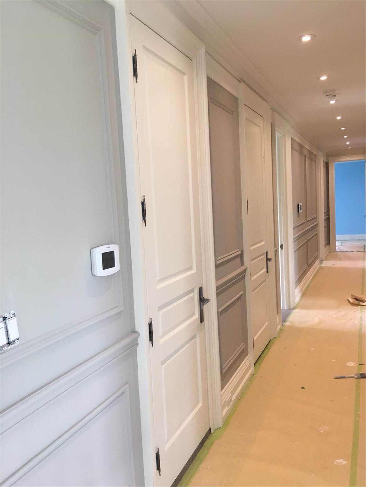 This image showcases a professional interior wall and trim painting project in Toronto, highlighting a long residential hallway with freshly painted doors, wall panels, and baseboards. Careful surface preparation and floor protection ensure clean edges and a smooth, consistent finish throughout the space. Neutral tones and detailed trim work create a bright, elegant corridor that enhances the home’s overall interior design. Completed by an experienced Toronto painting and renovation team, this project reflects precision craftsmanship and high-quality finishing for modern residential interiors.