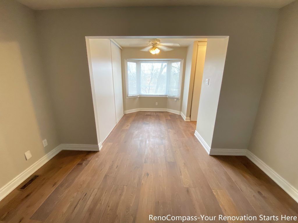 This Mississauga interior renovation features an open and well-connected living space finished with natural hardwood flooring and neutral wall tones. The wide opening enhances spatial flow between rooms, while the bay window brings in abundant natural light, creating a warm and inviting atmosphere. Clean lines and balanced proportions improve everyday functionality, making this renovated living area suitable for family living and long-term comfort.
