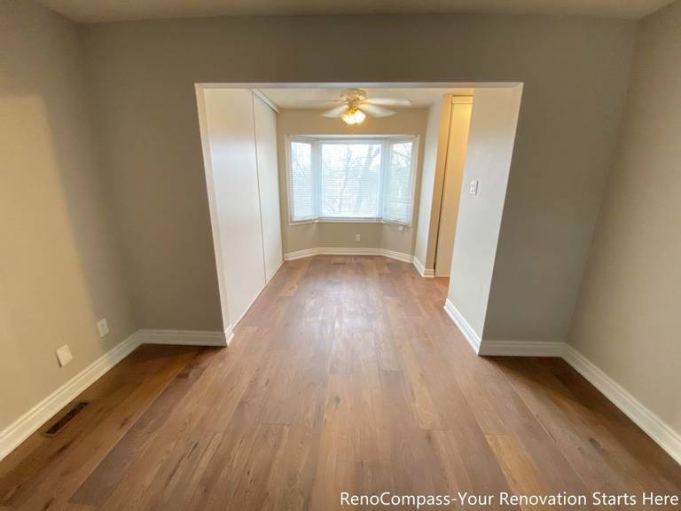 This Mississauga interior renovation features an open and well-connected living space finished with natural hardwood flooring and neutral wall tones. The wide opening enhances spatial flow between rooms, while the bay window brings in abundant natural light, creating a warm and inviting atmosphere. Clean lines and balanced proportions improve everyday functionality, making this renovated living area suitable for family living and long-term comfort.