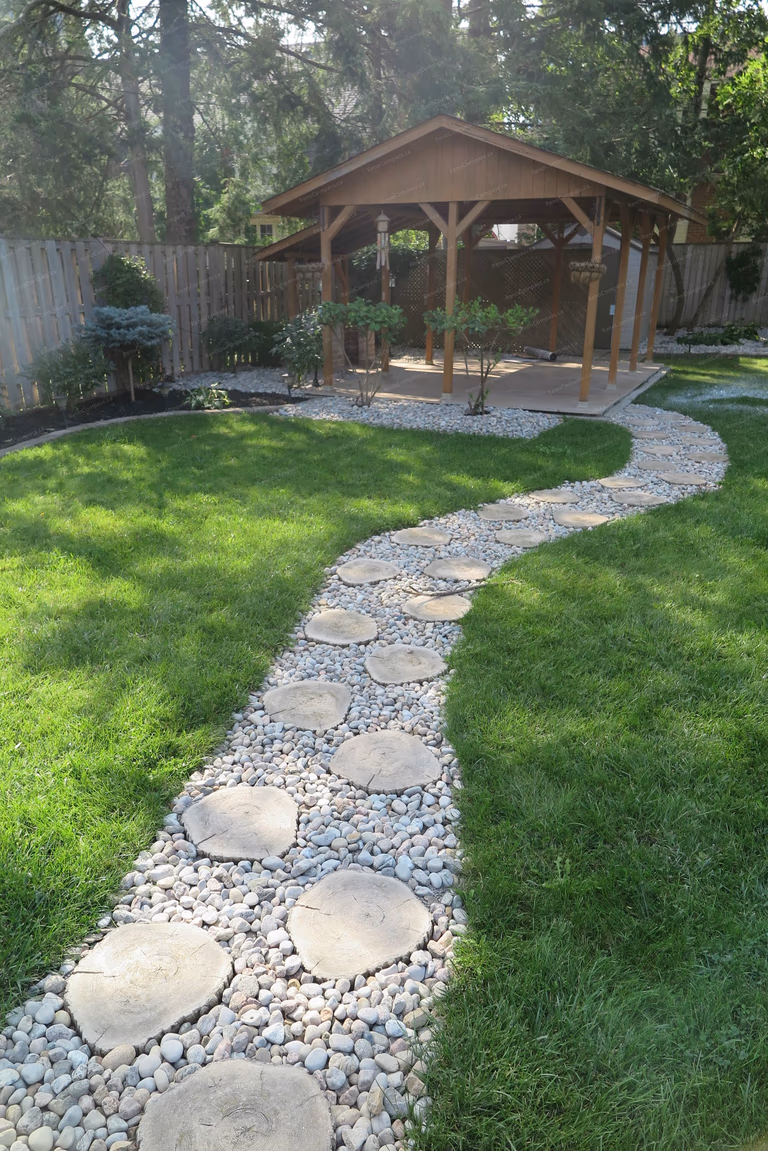 Beautiful North York outdoor landscaping project featuring a custom wooden garden pavilion, curved natural stone walkway, interlock retaining wall, and lush green lawn. Designed and built by Reno Compass to create a relaxing and functional backyard retreat with elegant garden structure and professional landscaping layout.