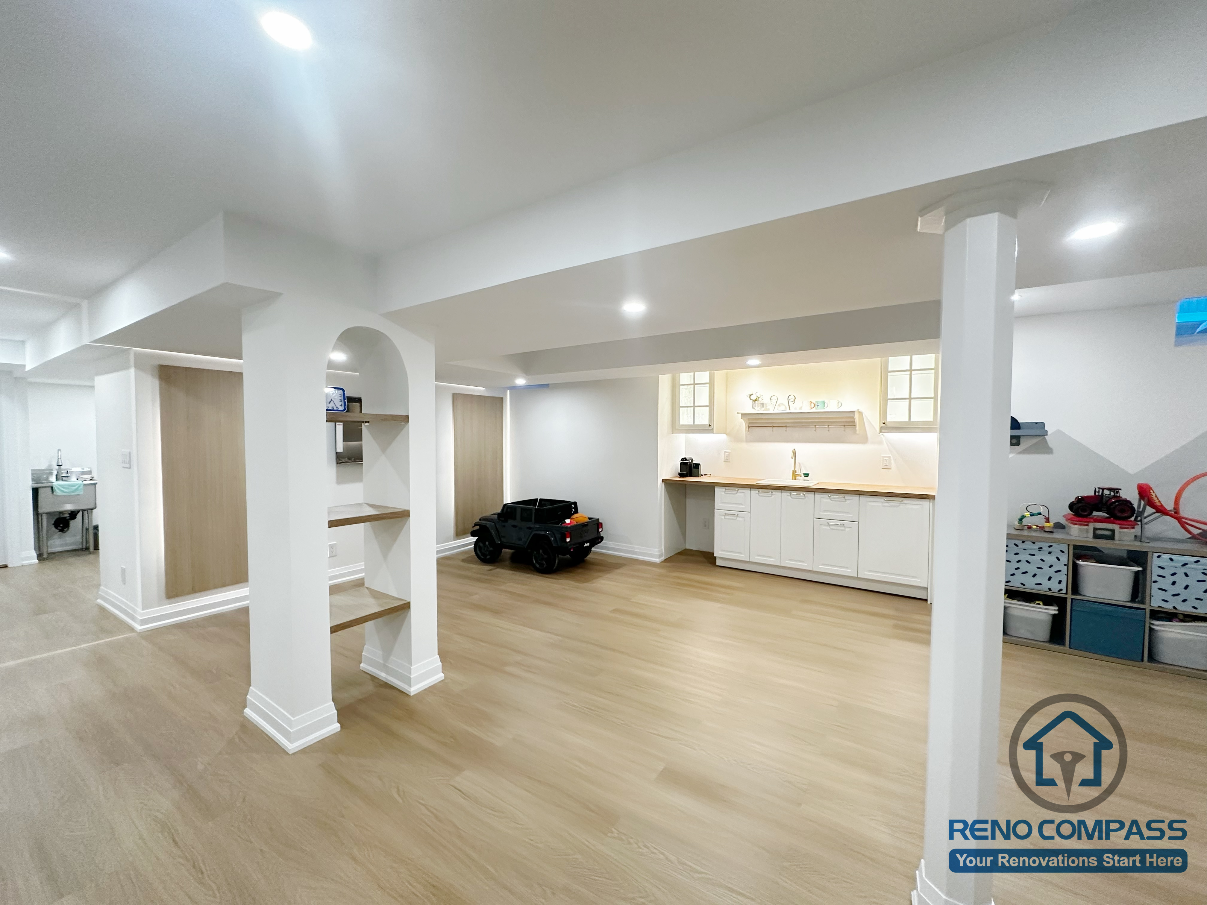 Open-concept basement renovation in Markham featuring light wood flooring, recessed ceiling lighting, and clean white support columns. The layout improves brightness, structural clarity, and flexibility for family living, recreation, and future customization.