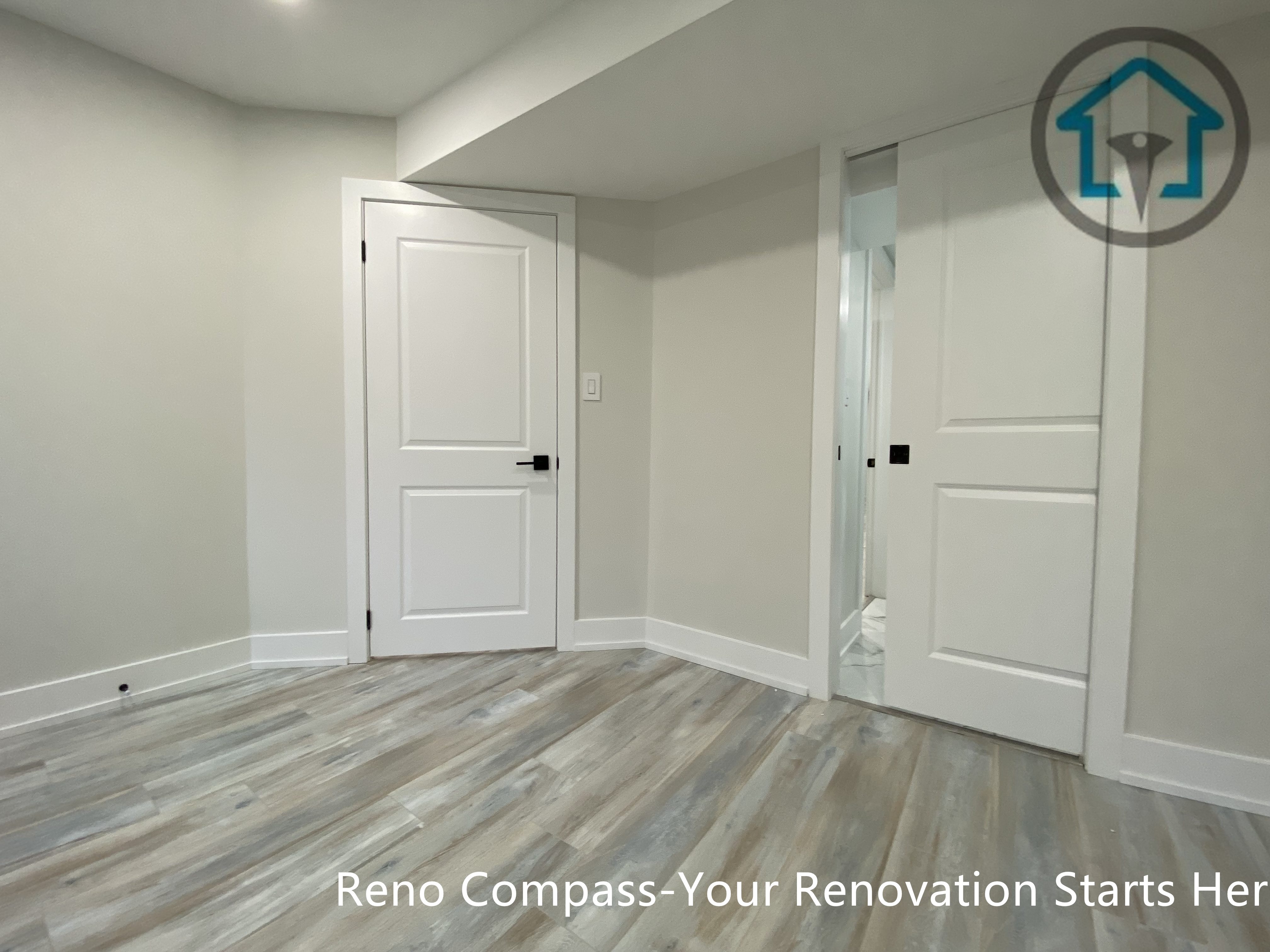 This Stouffville basement renovation showcases newly installed vinyl plank flooring, smooth drywall finishes, and modern interior doors with black hardware. The clean layout and neutral color palette create a bright, functional basement space suitable for bedroom, office, or family room use, completed by Reno Compass Inc.