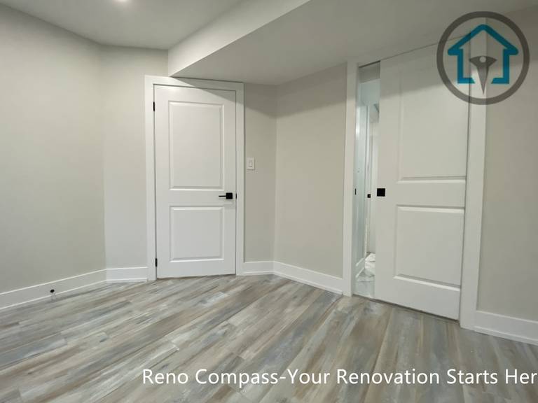 This Stouffville basement renovation showcases newly installed vinyl plank flooring, smooth drywall finishes, and modern interior doors with black hardware. The clean layout and neutral color palette create a bright, functional basement space suitable for bedroom, office, or family room use, completed by Reno Compass Inc.