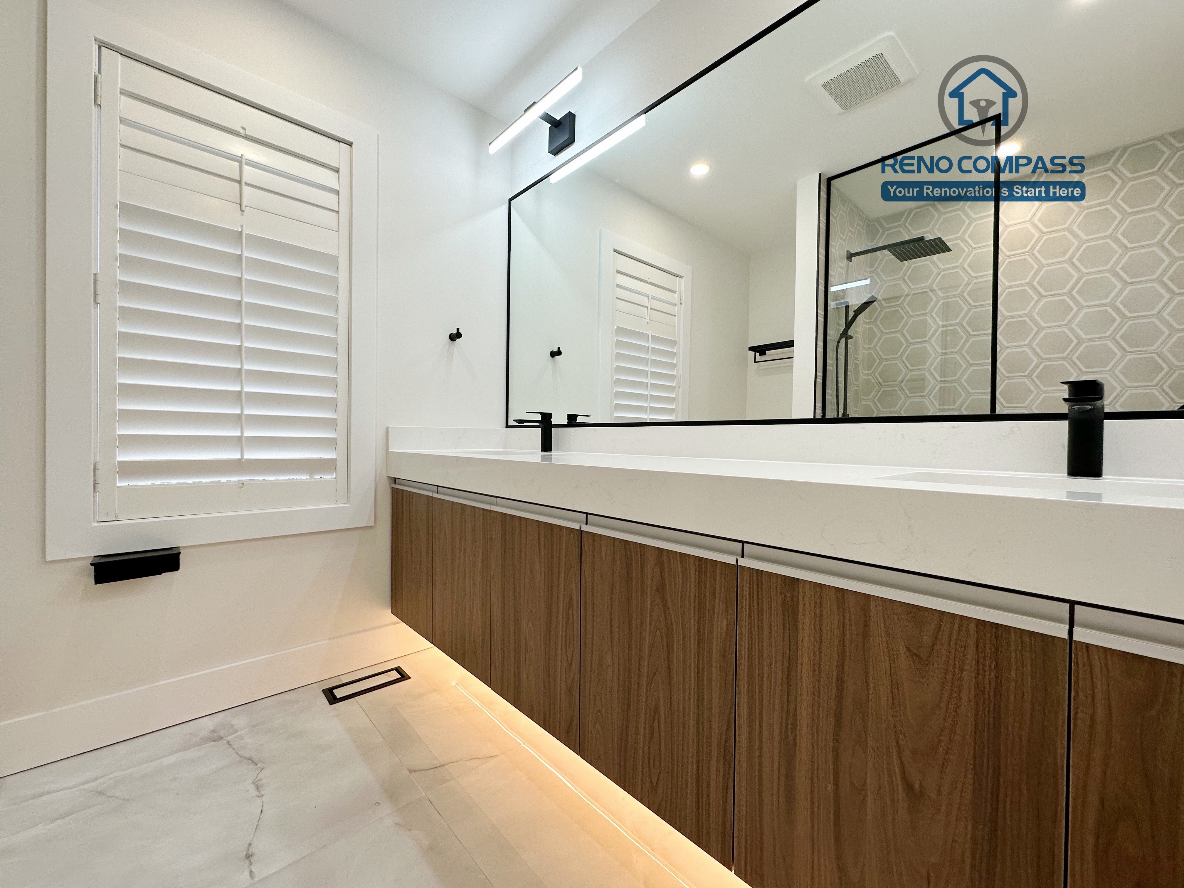 Modern bathroom renovation in Richmond Hill featuring a long floating double-sink vanity, integrated LED under-cabinet lighting, full-width mirror, and sleek black fixtures for a refined and contemporary finish.