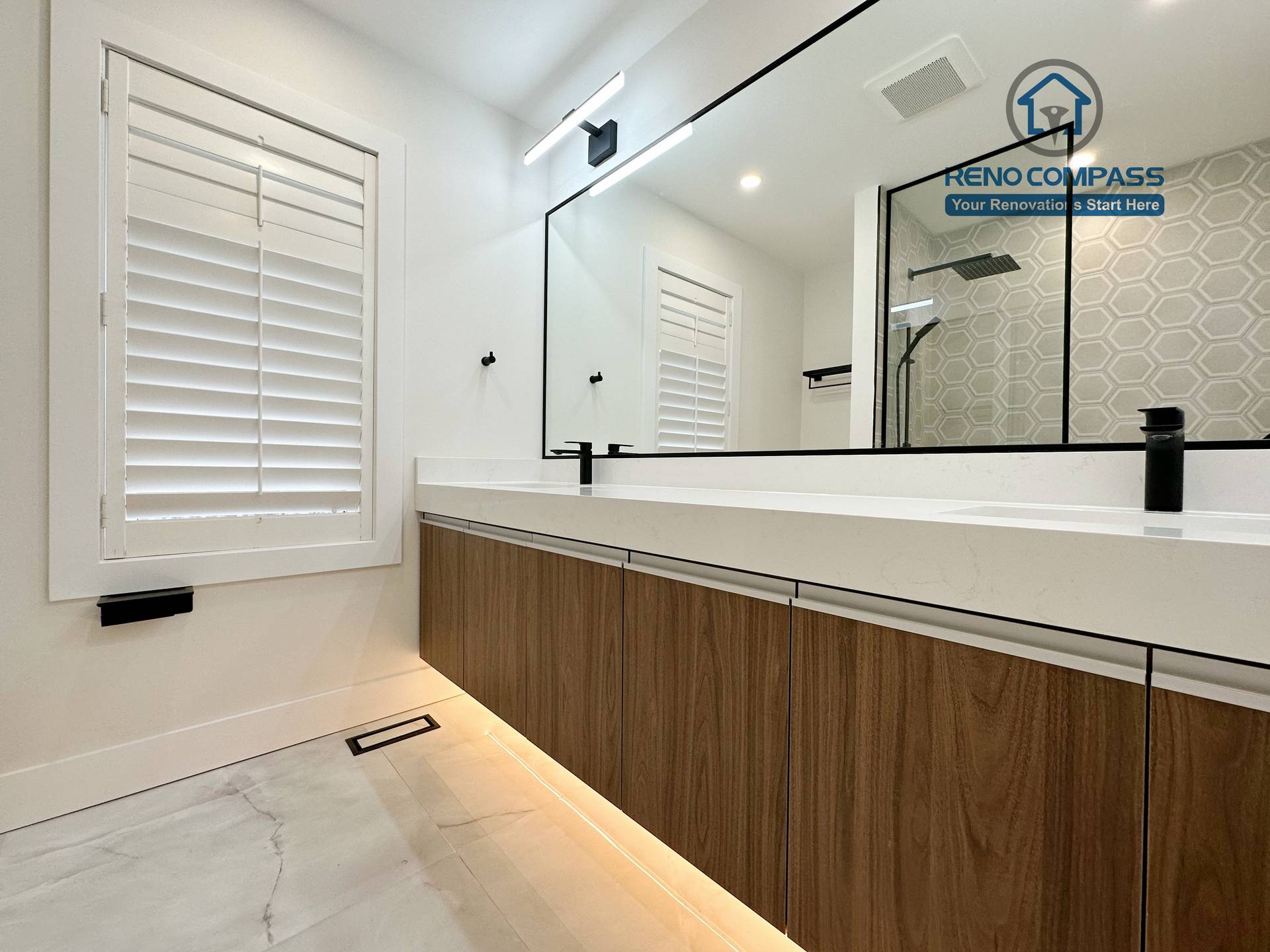 Modern bathroom renovation in Richmond Hill featuring a long floating double-sink vanity, integrated LED under-cabinet lighting, full-width mirror, and sleek black fixtures for a refined and contemporary finish.