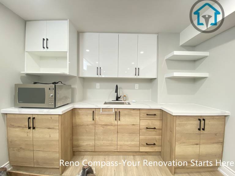 A custom basement kitchen area designed as part of a full basement renovation in Stouffville. This space features two-tone cabinetry, quartz countertops, integrated storage, open shelving, and functional workspace planning suitable for daily use or entertaining.