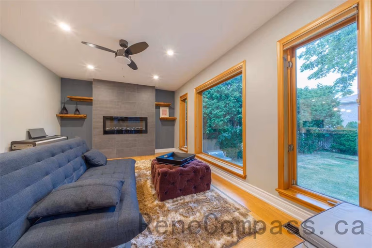 This family room is part of a North York interior renovation, designed to create a warm and inviting space for everyday living and relaxation. The room features a modern built-in fireplace wall, recessed ceiling lighting, and a ceiling fan for comfort and airflow. Large picture windows and a full-height glass door bring in abundant natural light and connect the interior to the backyard. Thoughtful layout planning, natural wood finishes, and clean modern details reflect the quality and functionality expected from professional Toronto interior renovation projects.