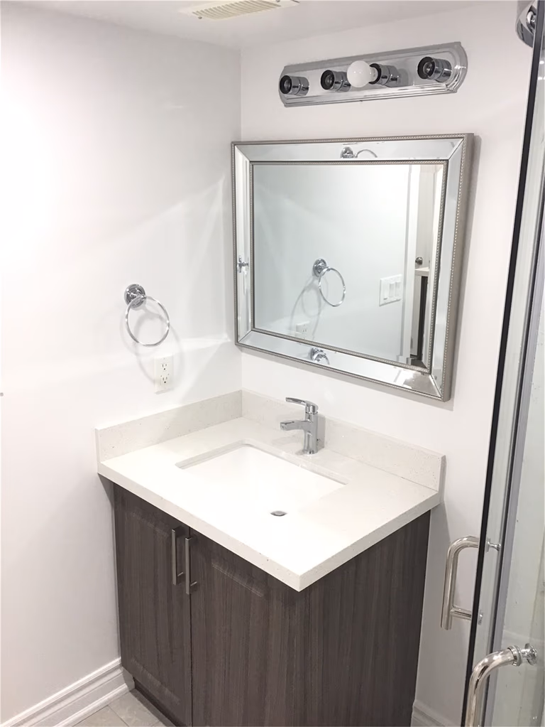 This Mississauga basement renovation includes a compact and modern kitchenette featuring dark wood cabinets, a sleek quartz countertop, and marble-style backsplash. The efficient layout maximizes functionality, making it perfect for a secondary suite, rental unit, or in-law living space.