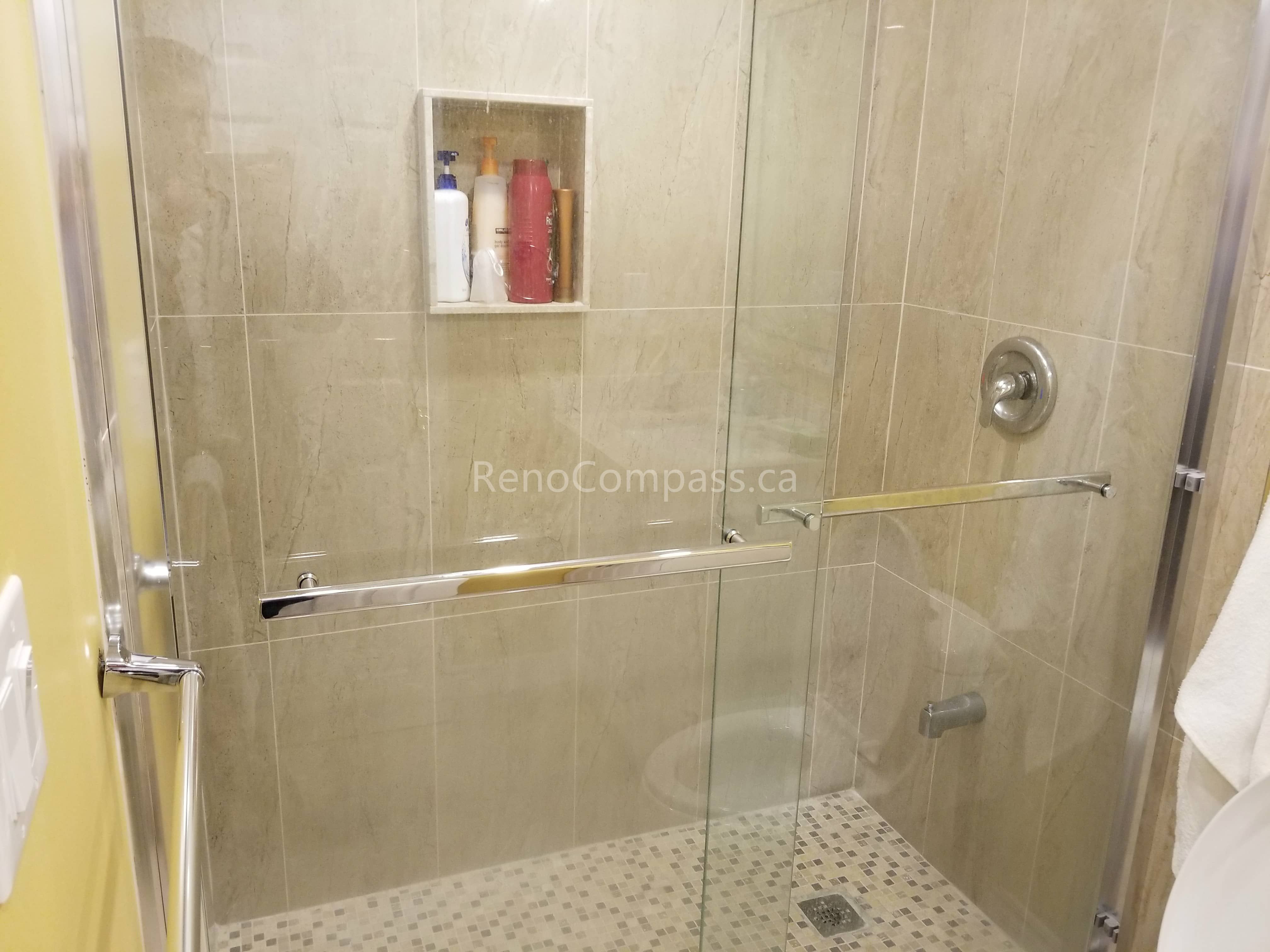 This Vaughan basement renovation features a newly upgraded bathroom with a modern glass shower enclosure, large-format wall tiles, and a built-in shower niche for convenient storage. The slip-resistant shower floor and clean, neutral-toned tile design create a bright, functional, and elegant space. Professionally completed by Reno Compass Inc., this basement bathroom upgrade enhances comfort, durability, and overall home value.