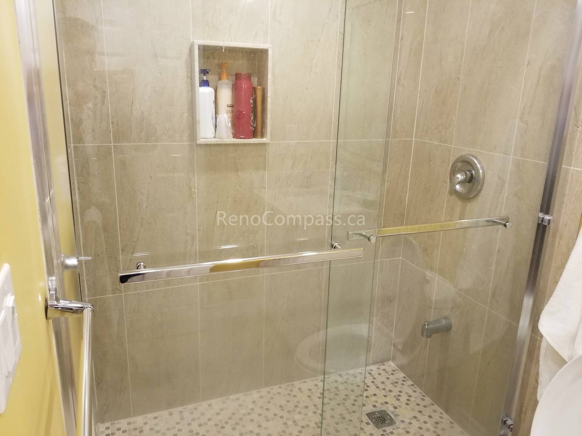 This Vaughan basement renovation features a newly upgraded bathroom with a modern glass shower enclosure, large-format wall tiles, and a built-in shower niche for convenient storage. The slip-resistant shower floor and clean, neutral-toned tile design create a bright, functional, and elegant space. Professionally completed by Reno Compass Inc., this basement bathroom upgrade enhances comfort, durability, and overall home value.