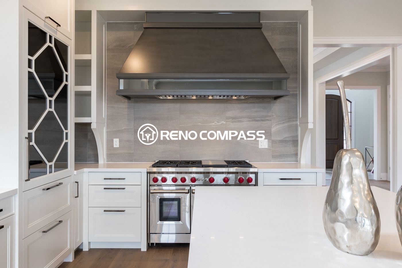 This luxury kitchen renovation in Newmarket showcases custom white cabinetry, a large quartz island, engineered wood flooring, and a professional-grade stainless steel range hood. The design combines elegant finishes with a functional layout, creating a bright and modern cooking space. Completed by a trusted Toronto renovation company, Reno Compass Inc., this project highlights high-end craftsmanship and contemporary kitchen design.