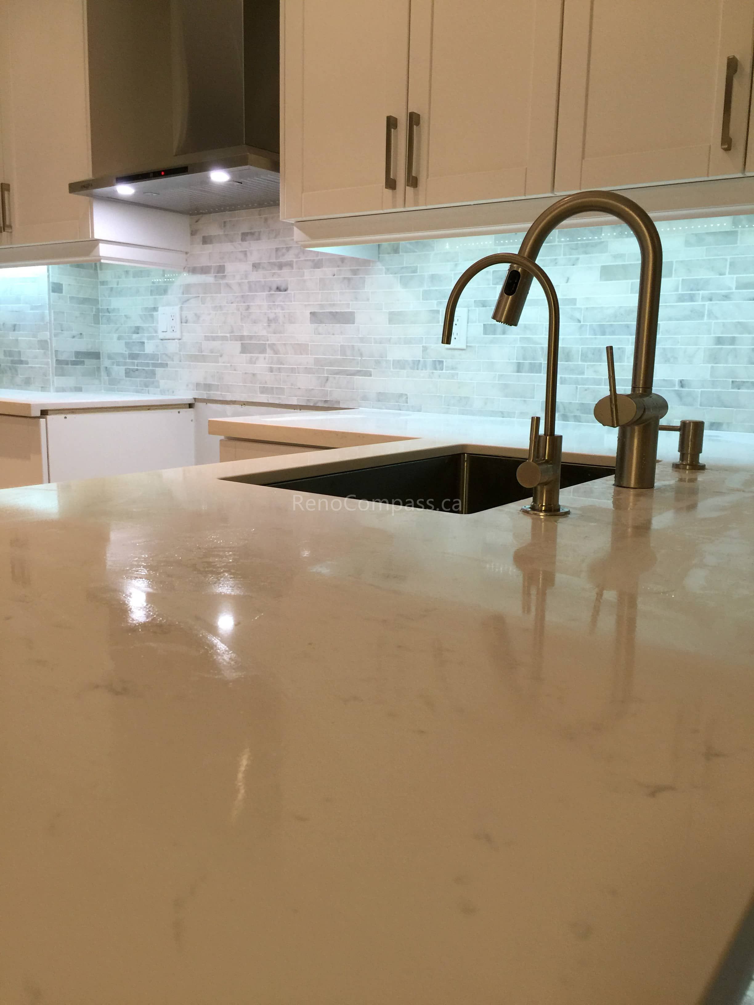 A close-up view of a modern kitchen interior renovation in Toronto showcasing a quartz island countertop, contemporary faucet, and under-cabinet LED lighting. The design highlights clean craftsmanship, durable materials, and refined details, representing high-quality Toronto interior renovation and interior design work.