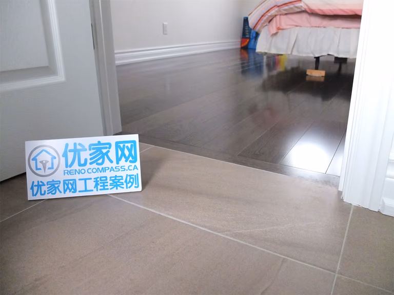 Bedroom entrance area from a Scarborough home addition project showing the transition between ceramic floor tiles and dark hardwood flooring. The renovation highlights clean trim work, smooth floor integration, and modern interior finishes designed for durability and visual continuity.