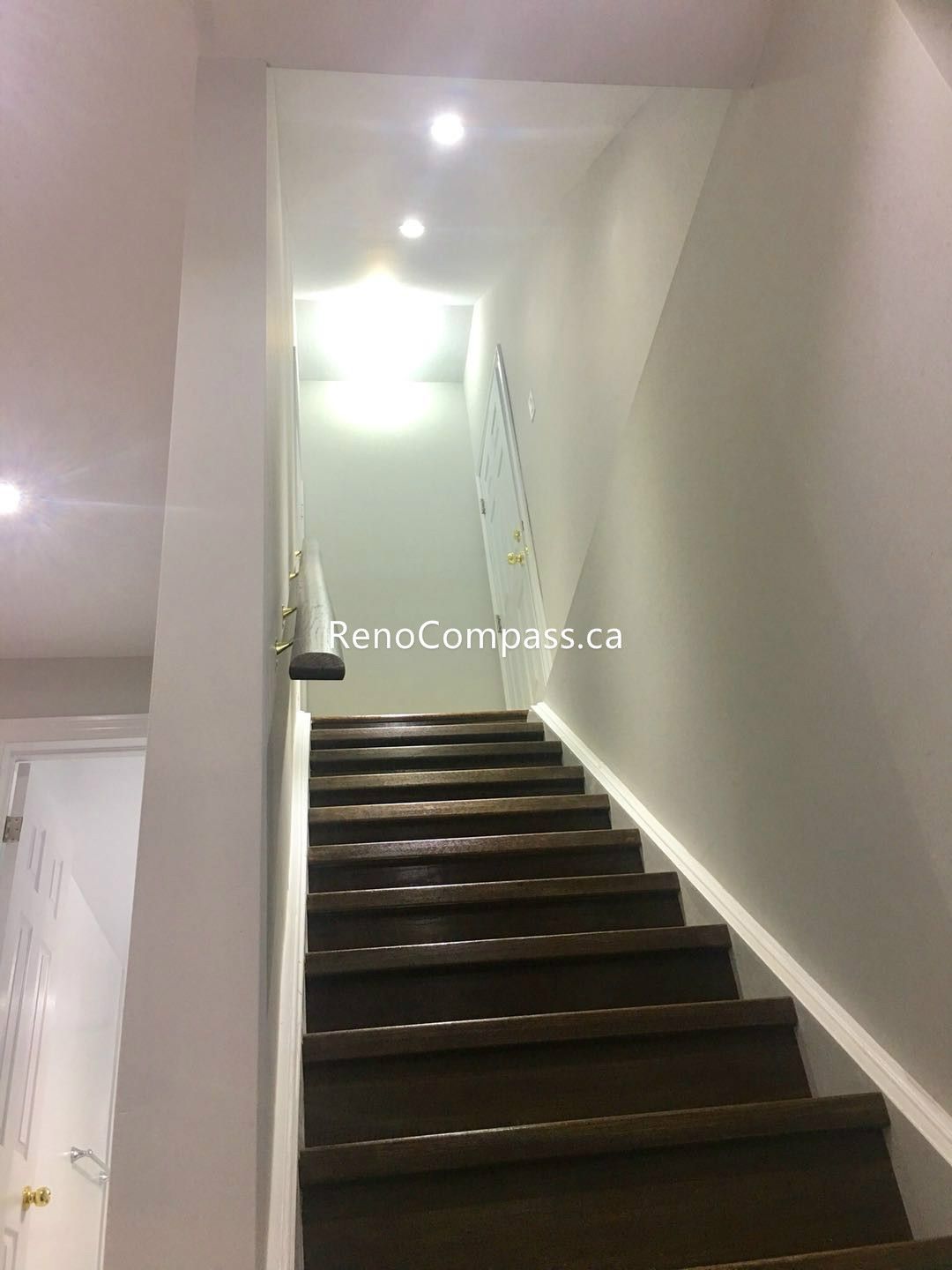 This Toronto basement renovation features a newly upgraded staircase with rich dark wood steps, clean white walls, and modern recessed pot lights for a bright and welcoming look. The refreshed stairway design improves safety, lighting, and visual flow between levels, creating a sleek and contemporary transition into the finished basement. Completed by a professional Toronto renovation company, the project highlights quality craftsmanship and modern interior finishing.