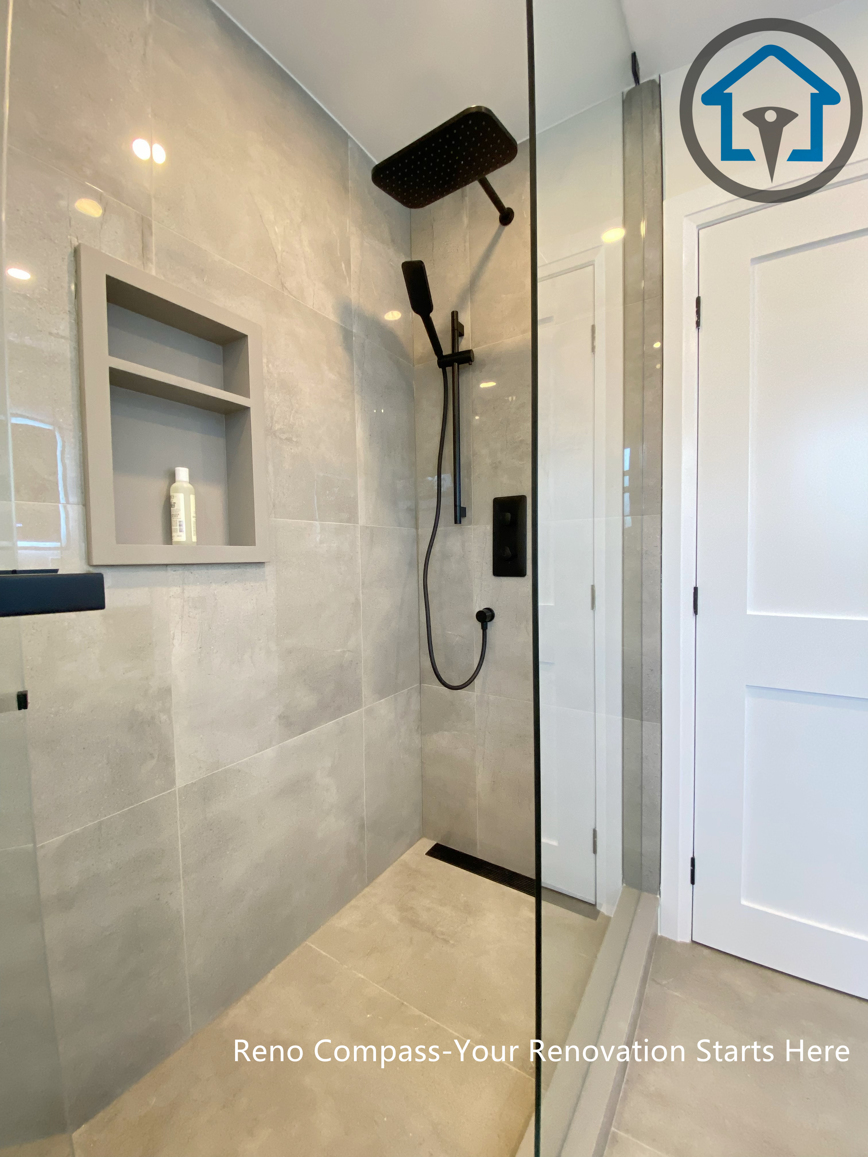 This North York house bathroom renovation highlights a walk-in glass shower with a built-in wall niche and matte black fixtures. Large-format tiles and a frameless glass enclosure create a clean, streamlined look, while the recessed niche adds practical storage without interrupting the overall design.