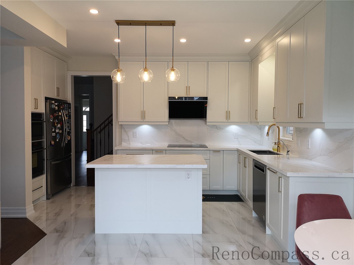This Aurora kitchen renovation features a bright open-concept layout with custom white shaker cabinets, quartz countertops, and a spacious center island for everyday functionality. Elegant pendant lighting, marble-style flooring, and brushed gold hardware create a modern and luxurious atmosphere. Completed by a professional Toronto renovation company focused on high-quality craftsmanship, efficient layout design, and timeless interior finishes.