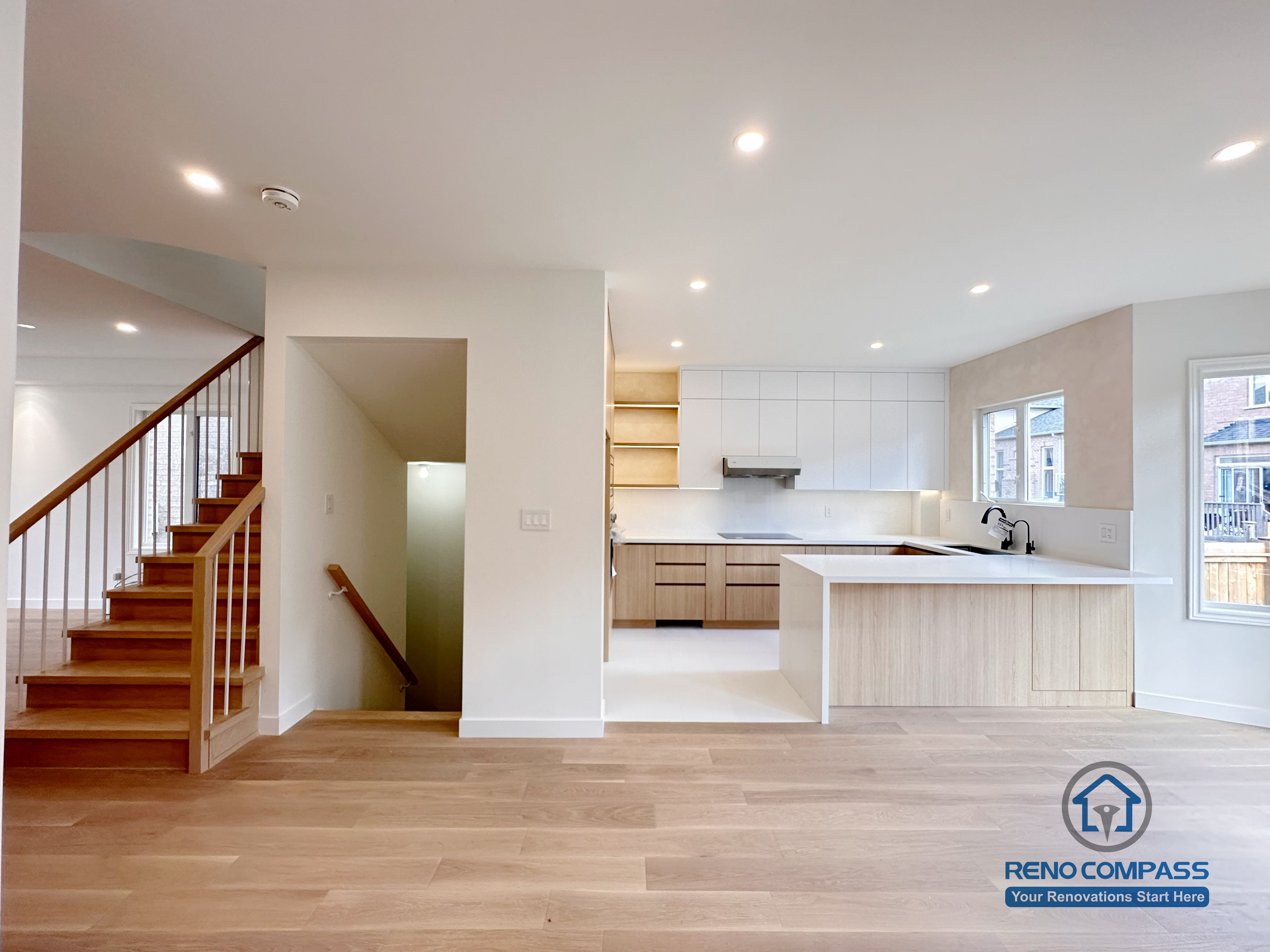 Open-concept main floor renovation in Markham showcasing a seamless connection between the kitchen, dining, and living areas. The design features a modern kitchen island, custom cabinetry, recessed lighting, and warm wood flooring to enhance spatial flow, natural light, and everyday functionality.