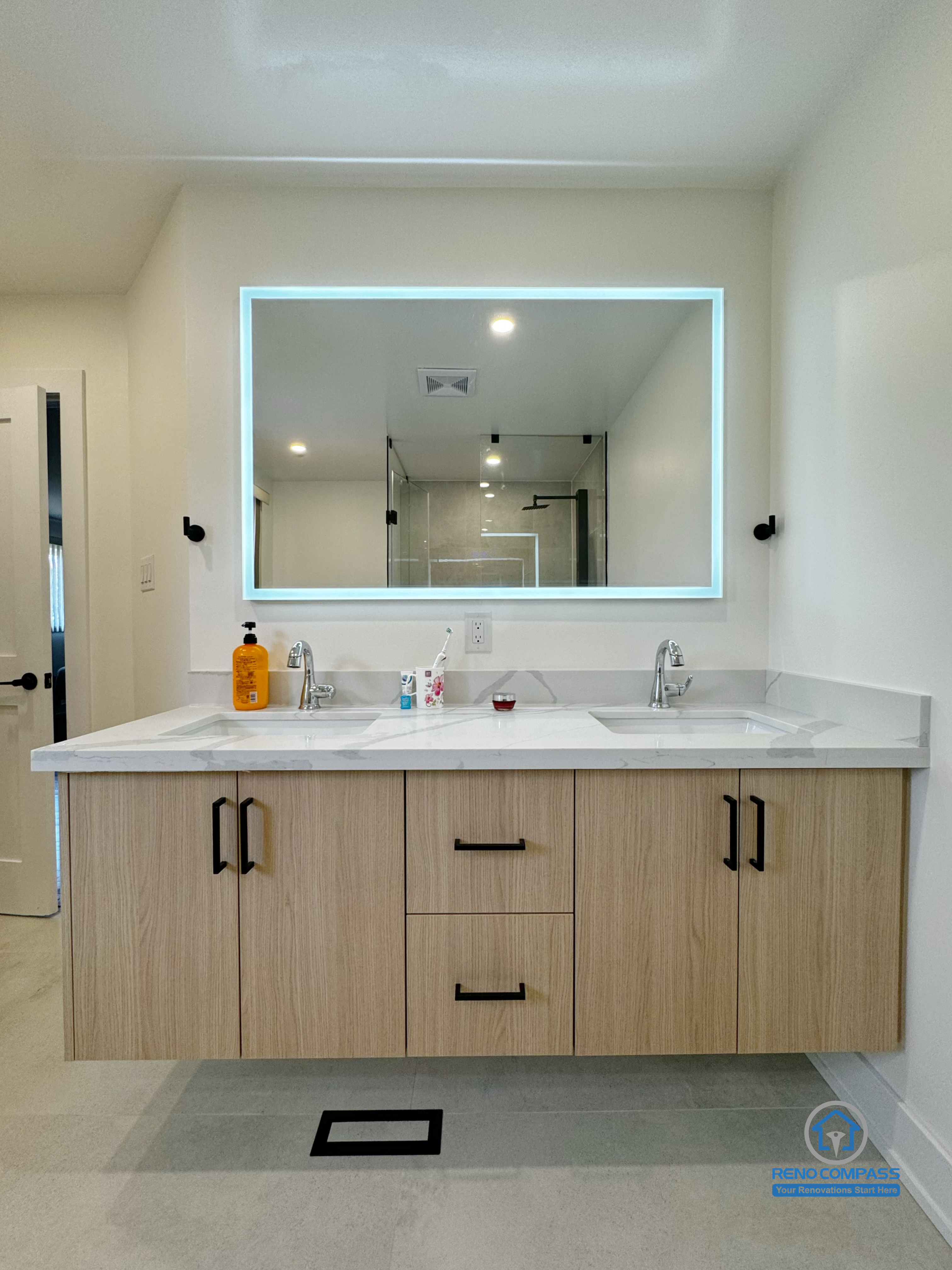 This Richmond Hill bathroom renovation features a modern double vanity with a floating wood cabinet, integrated storage, and a backlit mirror that enhances both functionality and visual balance. Clean lines, neutral finishes, and thoughtful lighting design create a bright, refined space suitable for daily family use. Completed as part of a Toronto renovation project focused on durability, comfort, and timeless interior design.