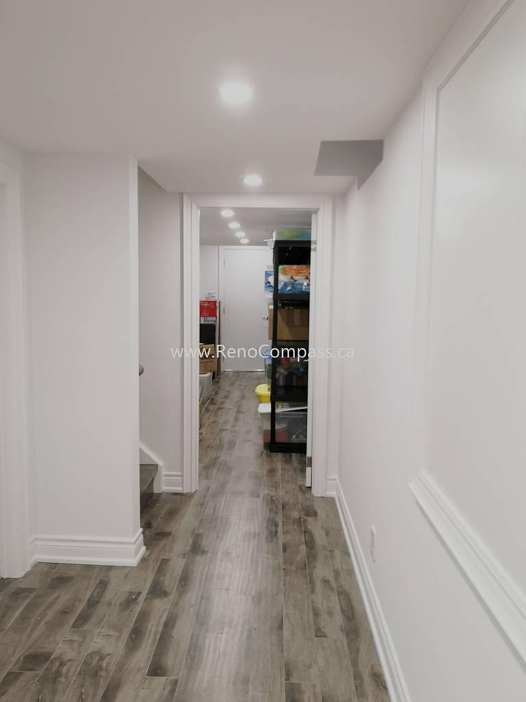 This Vaughan basement renovation features a clean and modern hallway design with durable wood-style flooring, smooth white walls, and recessed ceiling lighting for a bright and welcoming atmosphere. The upgraded basement corridor enhances overall flow and accessibility while maintaining a contemporary finish throughout the space. Completed by Reno Compass Inc., this renovation showcases quality craftsmanship and thoughtful design, creating a polished and functional basement living environment that complements the entire home renovation.
