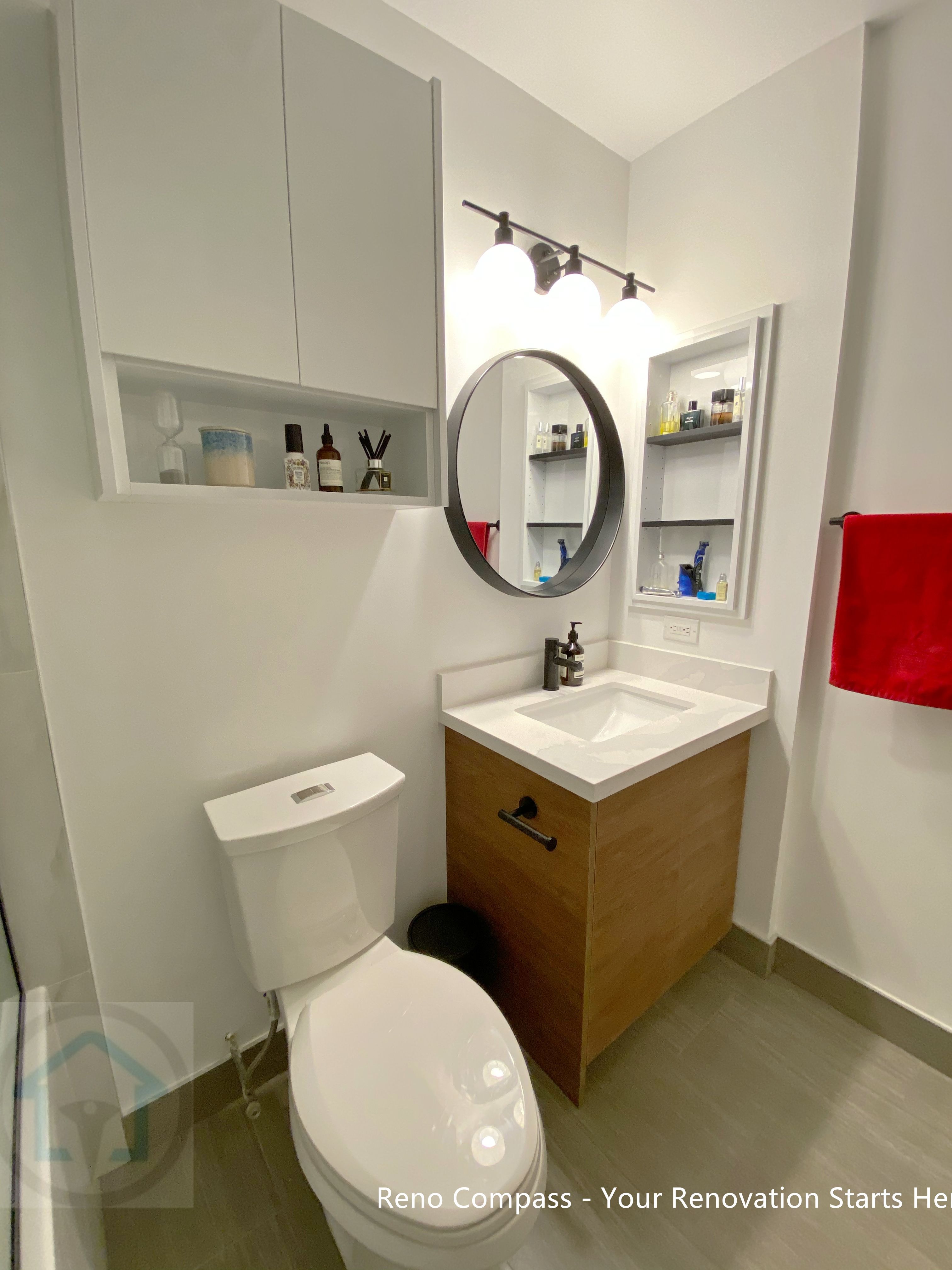 This modern condo bathroom features a custom vanity with warm wood-tone cabinetry, integrated storage niches, and a clean white countertop. The round mirror and wall-mounted lighting enhance brightness while maintaining a minimalist aesthetic. Thoughtful storage design improves daily functionality, making this bathroom renovation both practical and visually balanced for North York condo living.