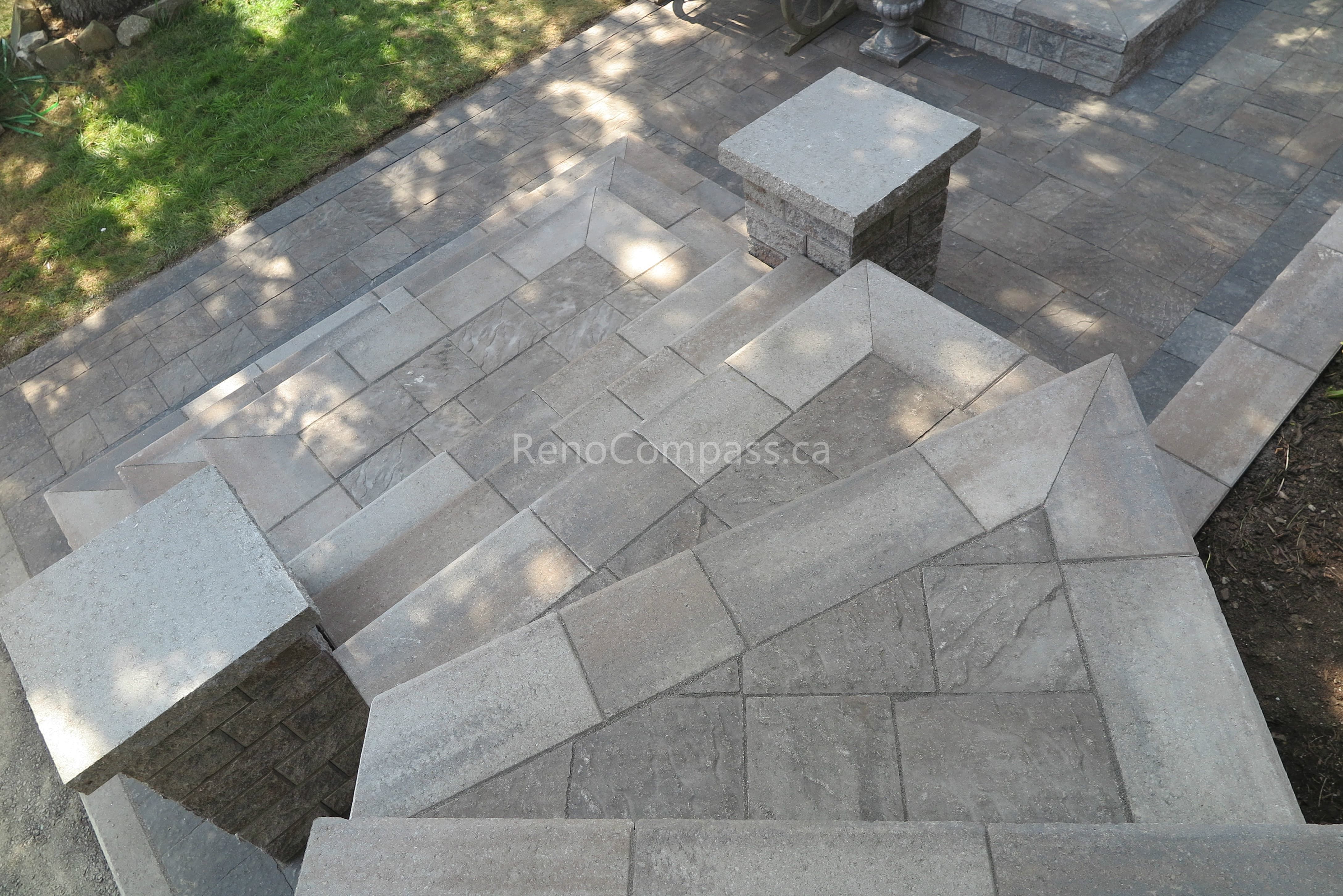 This Mississauga landscaping renovation showcases custom interlocking front entrance steps and landing patio designed for both visual impact and functionality. The multi-level stone layout creates a smooth transition from driveway to entrance while enhancing safety and flow. Premium interlocking pavers and stone columns add depth, structure, and a refined architectural feel to the exterior. Completed by Reno Compass Inc., this project highlights expert craftsmanship in residential interlocking and front yard landscaping design.
