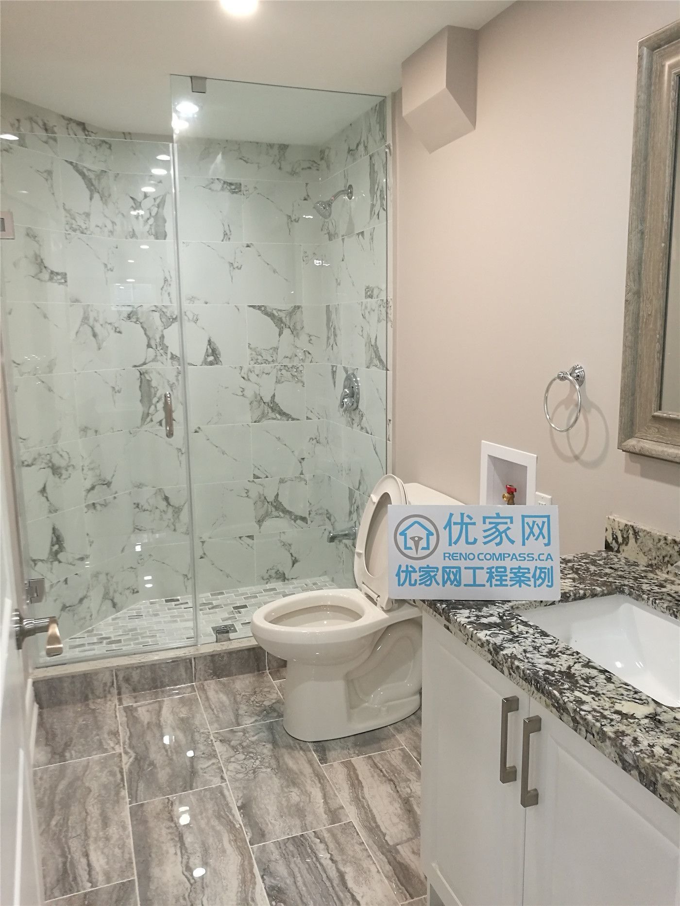 Modern basement bathroom renovation in Richmond Hill featuring a frameless glass shower, marble-look wall tiles, stone-finish floor tiles, custom vanity, and updated lighting. This basement bathroom remodel improves functionality, moisture protection, and overall space efficiency, completed by a professional Toronto renovation company.