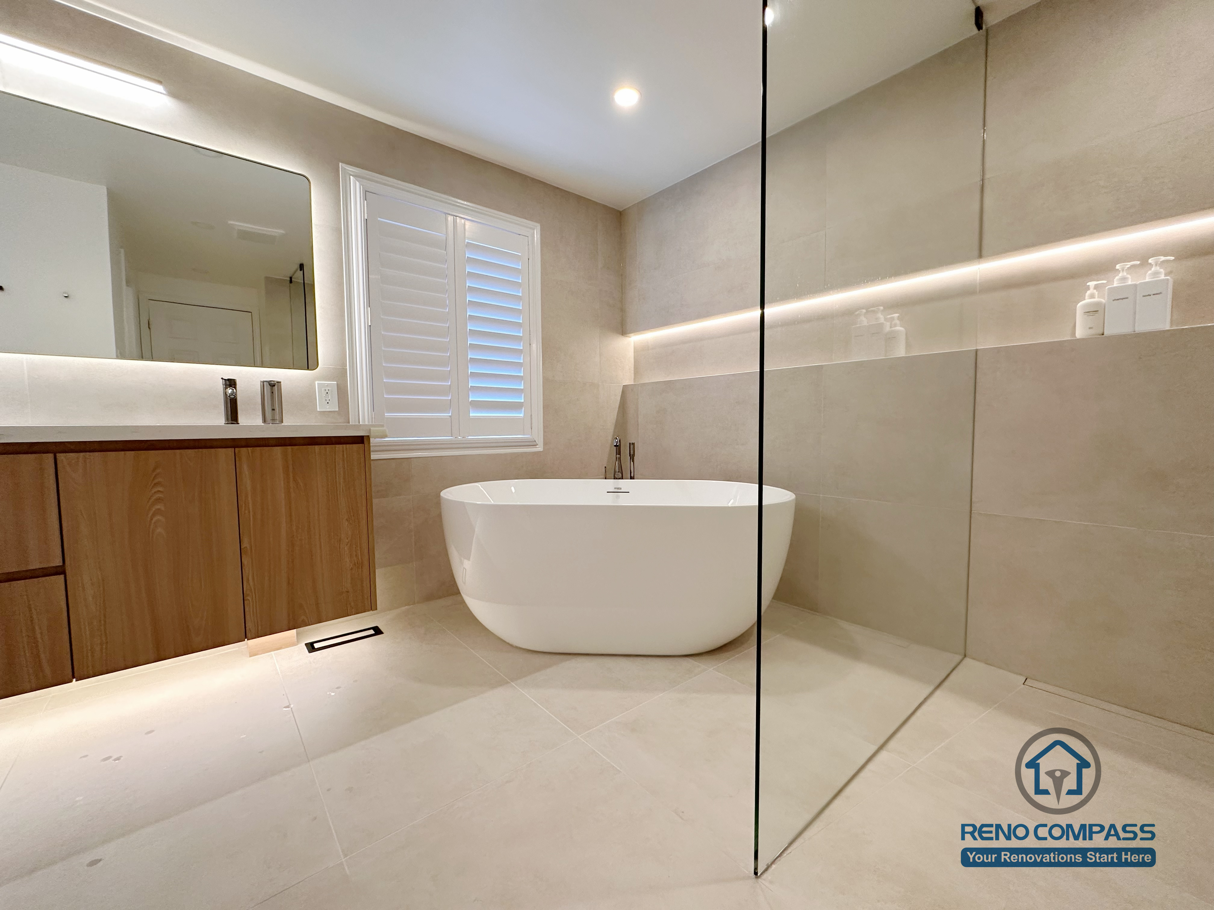This Markham accessible bathroom renovation features a freestanding bathtub positioned within a barrier-free layout, allowing easy movement and step-free access. Large-format floor and wall tiles, integrated linear lighting, and a custom wood-tone vanity contribute to a calm, safe, and modern environment. Designed and built by a professional Toronto renovation company, Reno Compass Inc., the space prioritizes accessibility, comfort, and long-term usability.
