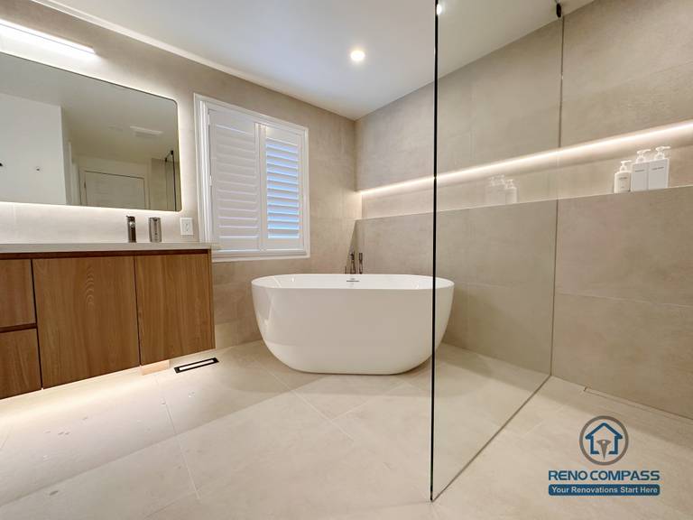 This Markham accessible bathroom renovation features a freestanding bathtub positioned within a barrier-free layout, allowing easy movement and step-free access. Large-format floor and wall tiles, integrated linear lighting, and a custom wood-tone vanity contribute to a calm, safe, and modern environment. Designed and built by a professional Toronto renovation company, Reno Compass Inc., the space prioritizes accessibility, comfort, and long-term usability.