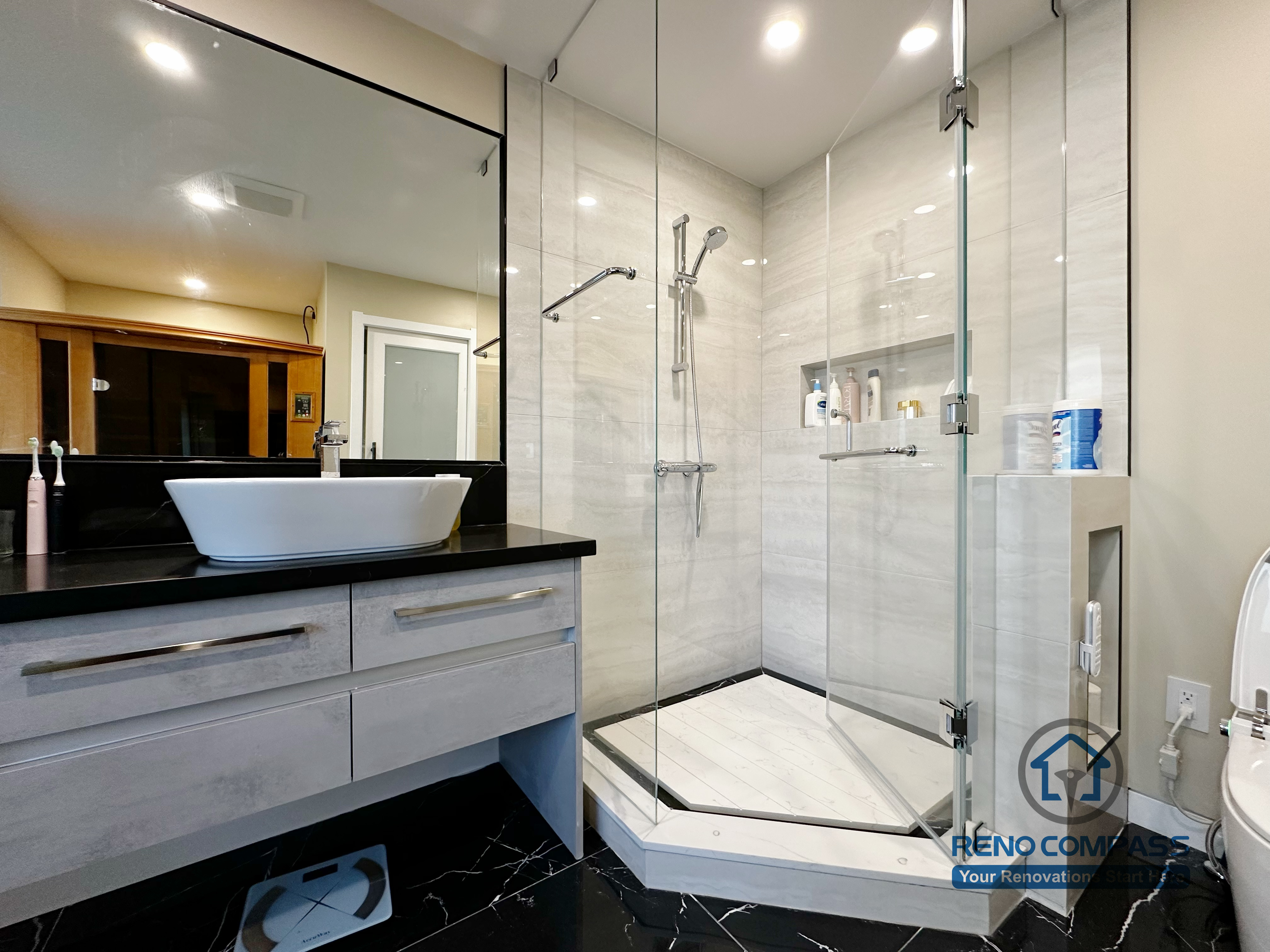 Bathroom vanity completed as part of a North York interior renovation. This design features a custom floating vanity, vessel sink, black countertop, and large wall mirror, paired with marble-look flooring and a glass shower enclosure. Built with a focus on durability, clean detailing, and daily usability by a professional Toronto renovation company.