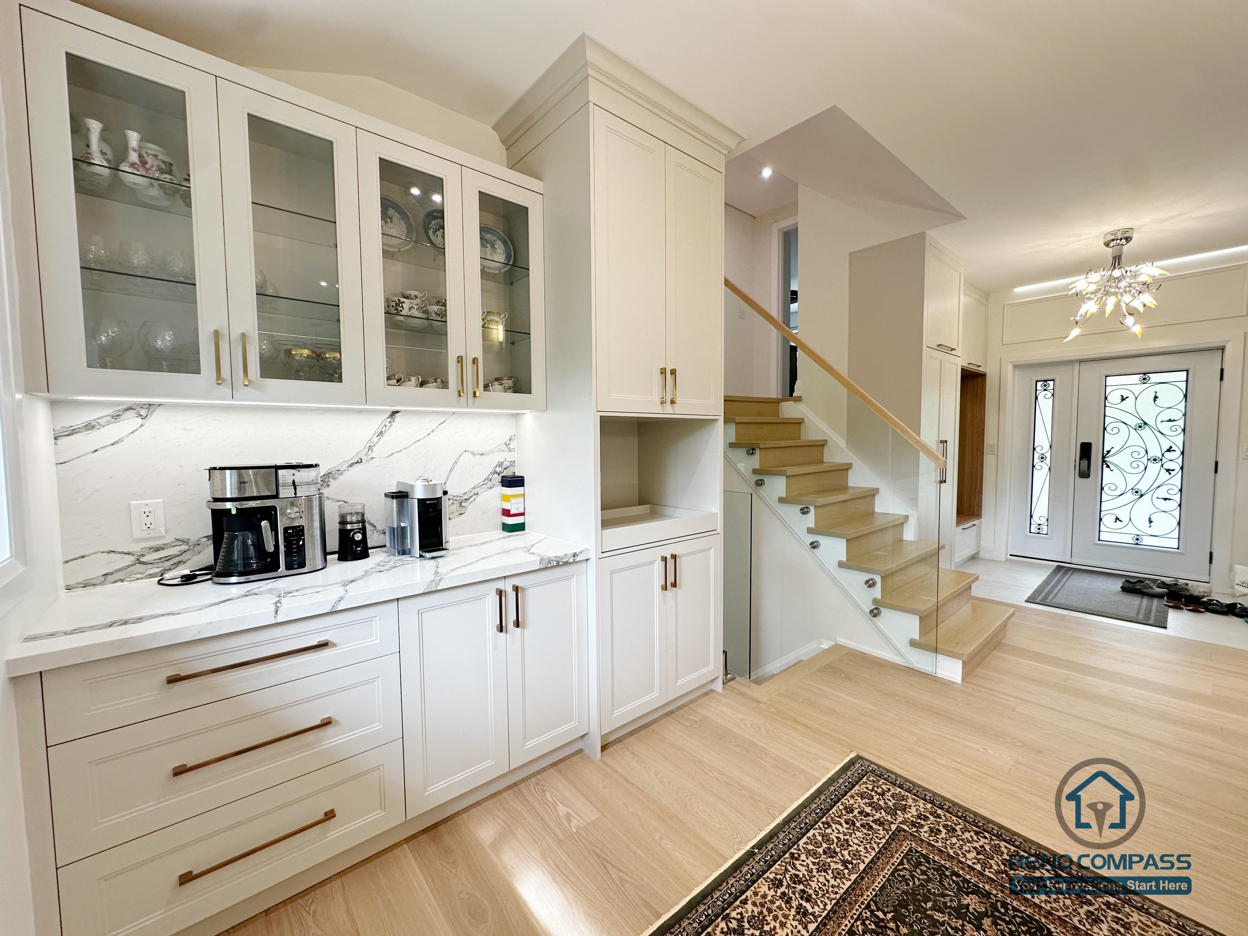 A clean and modern built-in coffee bar with glass uppers and marble backsplash. Gold hardware and soft lighting elevate the space, seamlessly connecting the entryway and staircase for a bright, open-concept layout.
内嵌式咖啡吧结合玻璃柜门、大理石背板与金色五金，整体简洁明亮。与楼梯及玄关区域自然衔接，打造通透、现代的开放式空间。