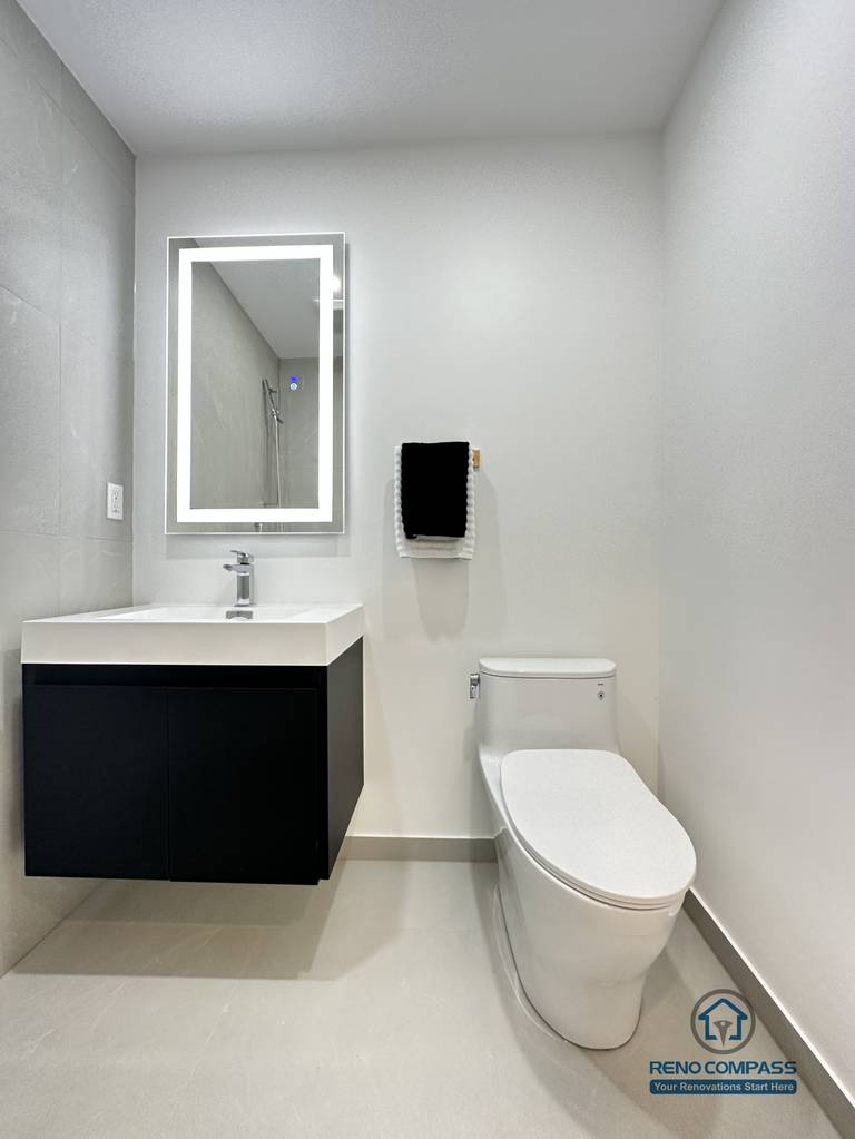 This image showcases a modern accessible pet shower bathroom renovation in Brampton, designed with a clean, barrier-free layout for ease of use. The space features large-format non-slip floor tiles, a wall-mounted floating vanity, an LED backlit mirror, and a compact toilet configuration to maximize maneuverability. The open shower area allows safe and comfortable bathing for pets while remaining fully accessible for homeowners. This type of thoughtful, functional design is ideal for aging-in-place and pet-friendly homes, completed by a professional Toronto Renovation Company with experience in accessibility-focused bathroom solutions.