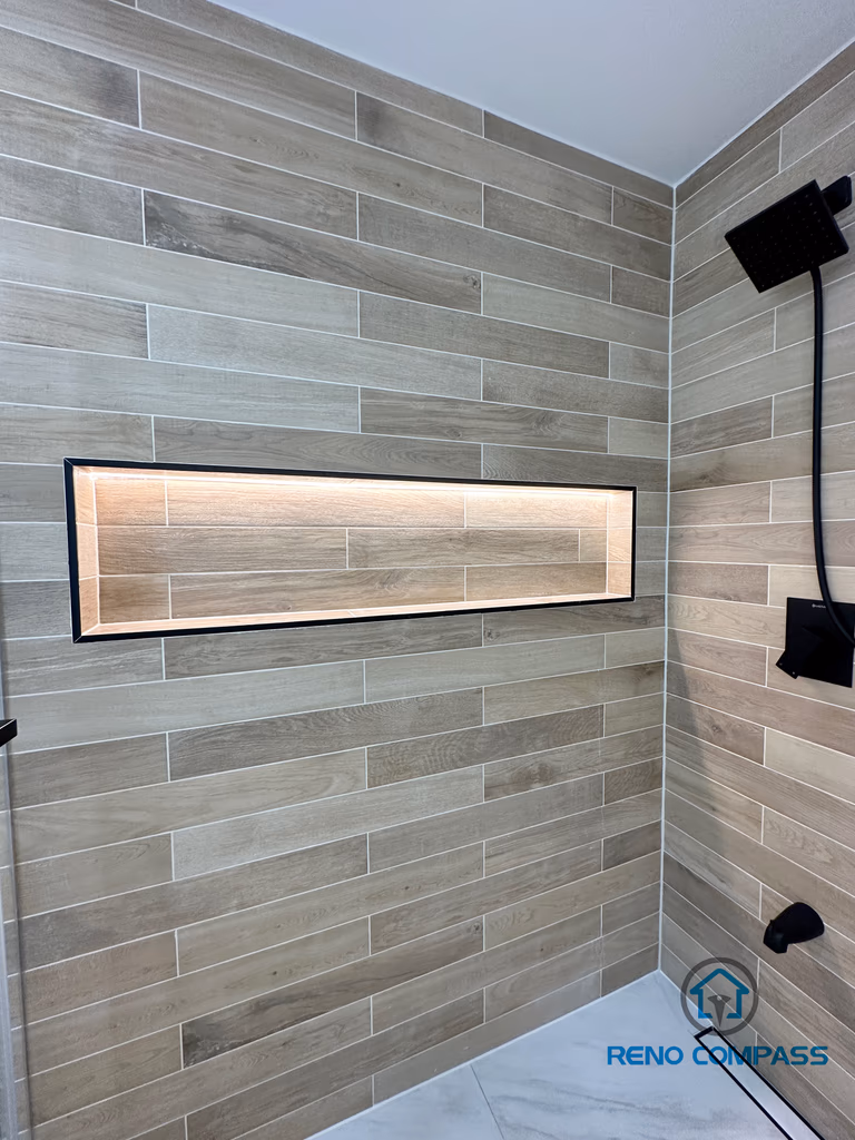 Modern bathroom renovation in Vaughan featuring a custom-built horizontal shower niche with integrated LED lighting. The shower wall is finished with wood-look porcelain tiles laid in a clean horizontal pattern, paired with matte black shower fixtures for a contemporary spa-style design. This project showcases detailed craftsmanship by a professional Toronto renovation company, combining functional storage with elegant lighting and premium tile installation.
